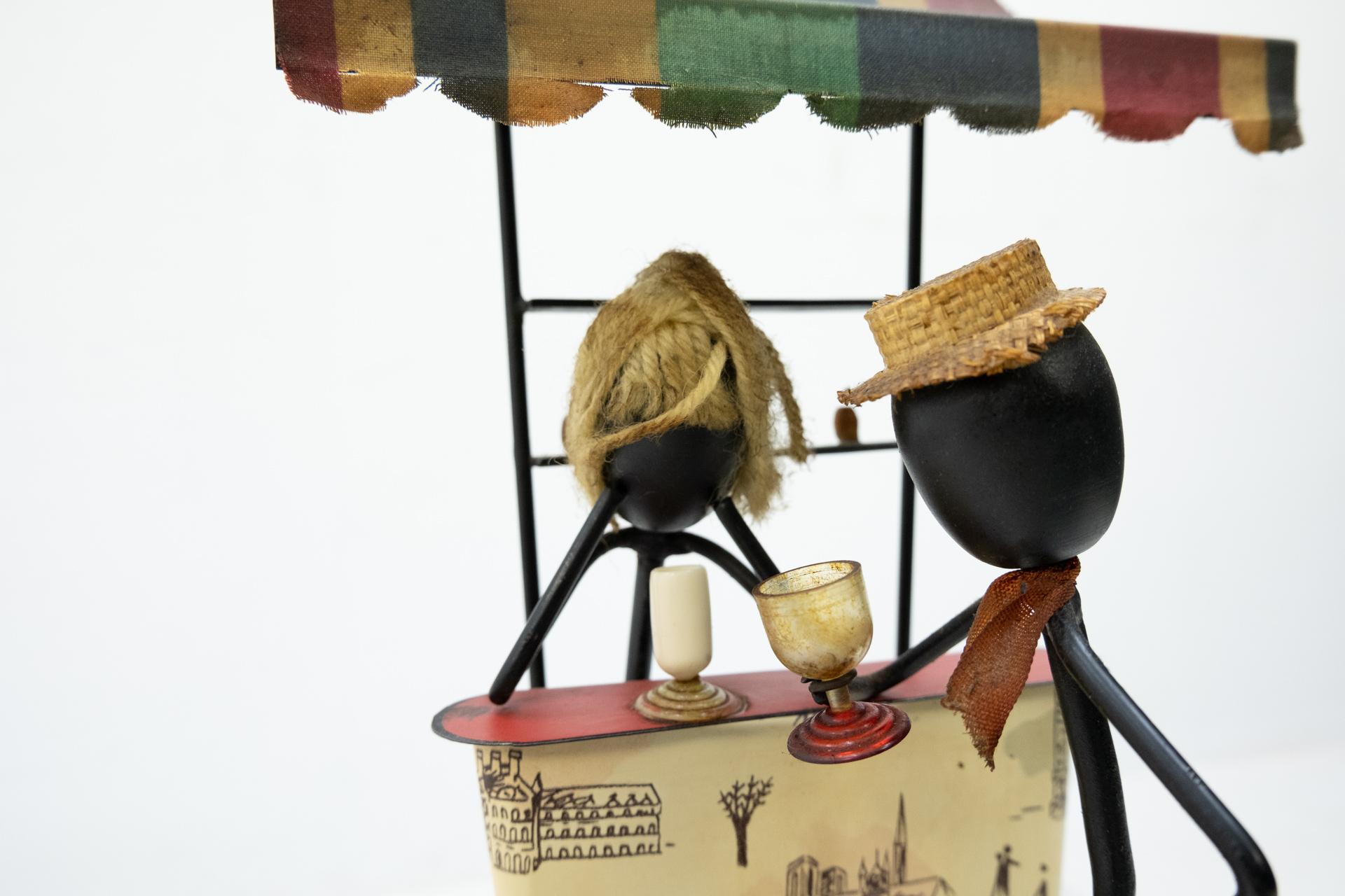 Small tinplate bar, with a bar lady, and a dandy customer in front of the bar. Drinking
a cocktail together. So much details in this little scenery, 1950s.