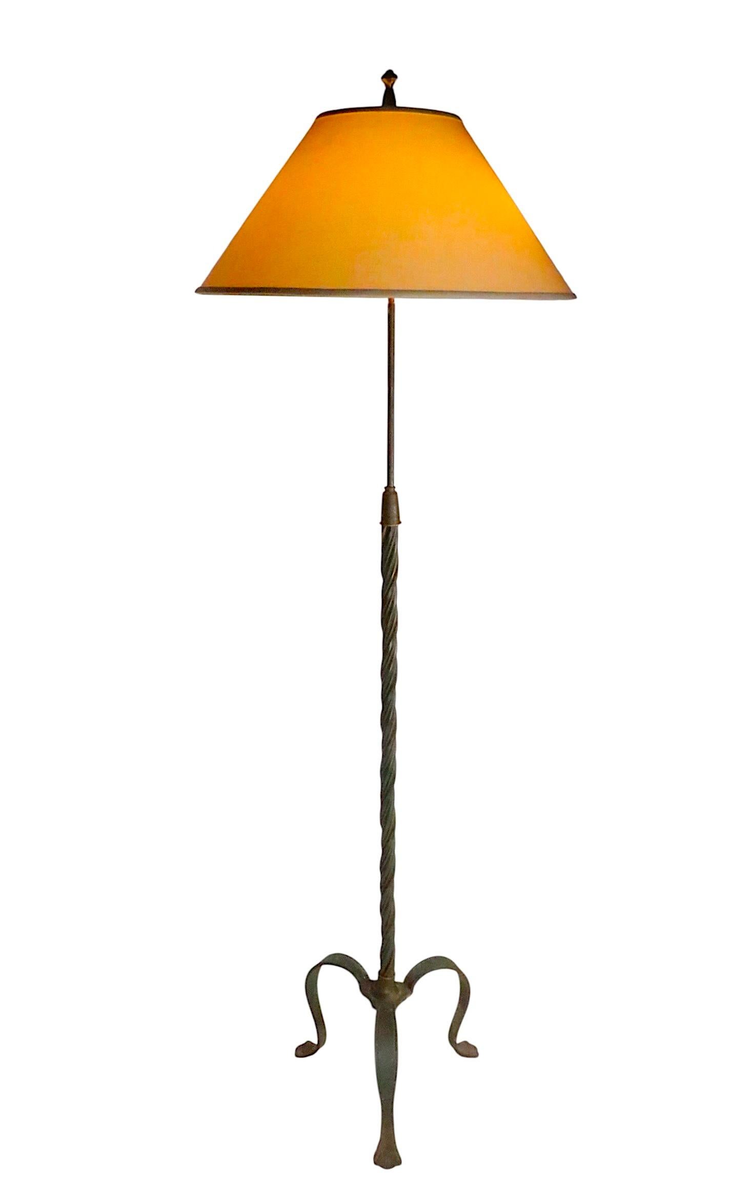 Außergewöhnliche Stehlampe aus Metall, mit einem gedrehten vertikalen Metallmast mit messingfarbenen und grün lackierten Eisenfäden, die einen grafischen visuellen Effekt erzeugen. Der Sockel besteht aus drei Eisenbeinen mit verzierten,