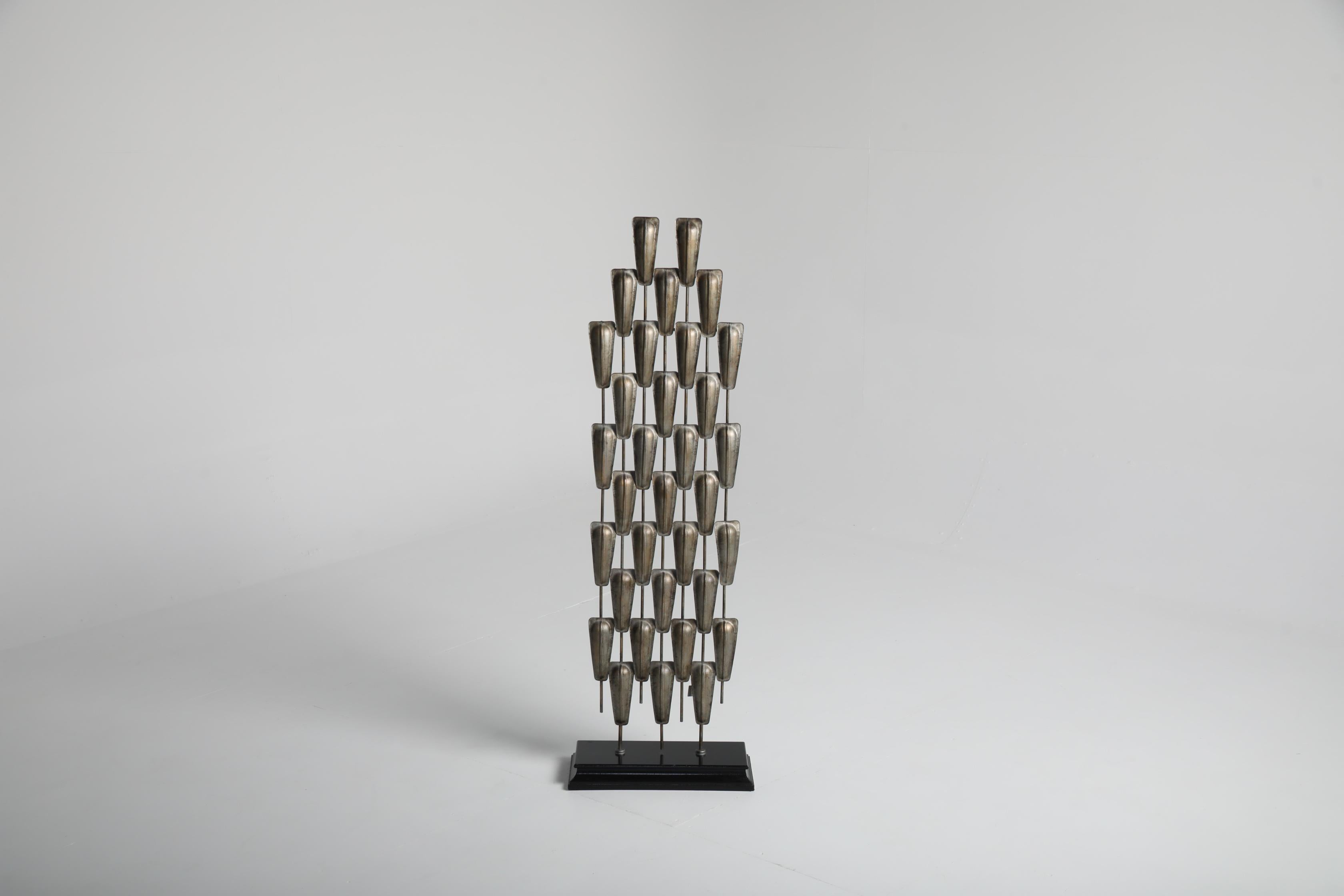 Cet objet sculptural pour le sol a été produit au Danemark dans les années 1980 et distribué par la célèbre Collectional. La pièce présente une composition verticale frappante d'éléments métalliques répétés montés sur une base en bois solide, créant