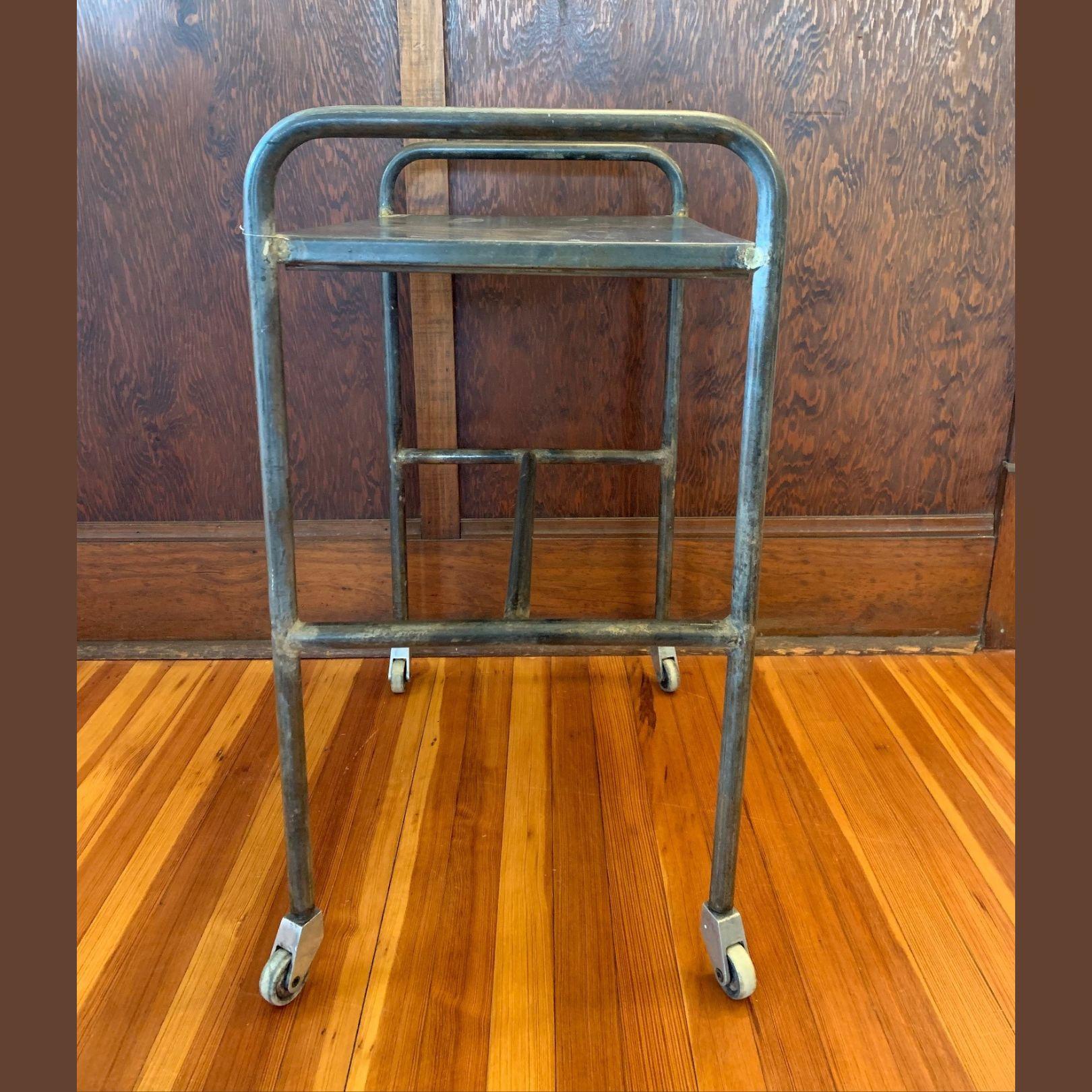 This distressed vintage metal table would make a beautiful addition to any living room, den, or office. Crafted in the United States circa 1990 and made of industrial brushed steel, the table sits on four well-oiled wheels with a stretcher to