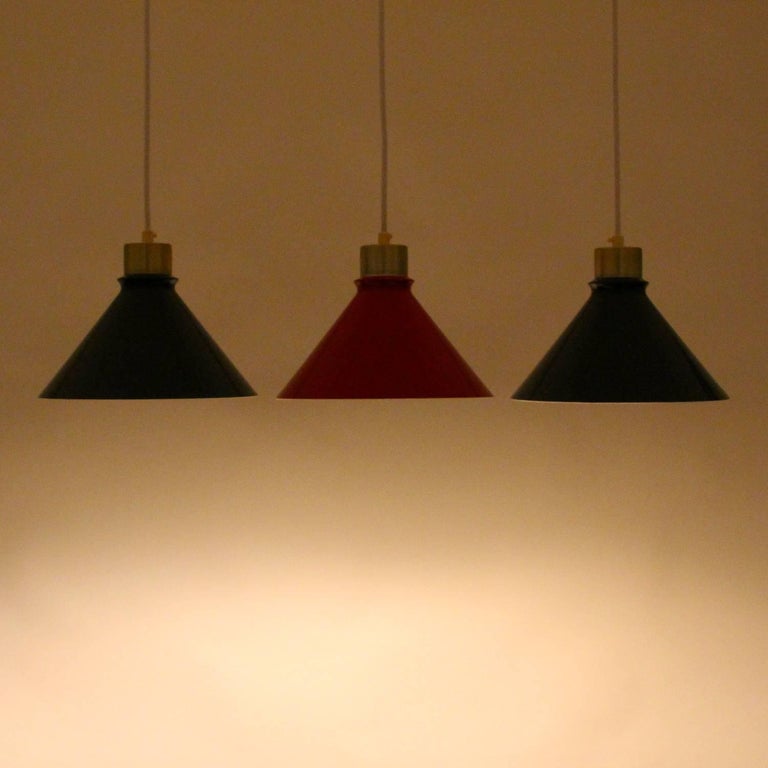 Metal pendant lights (set of three), 1960s Danish modern ceiling lights with green and red enamel and brass lacquered tops by unknown producer.

A stylish set of enameled metal pendants, each pyramid shaped with a cylindrical brass lacquered top.