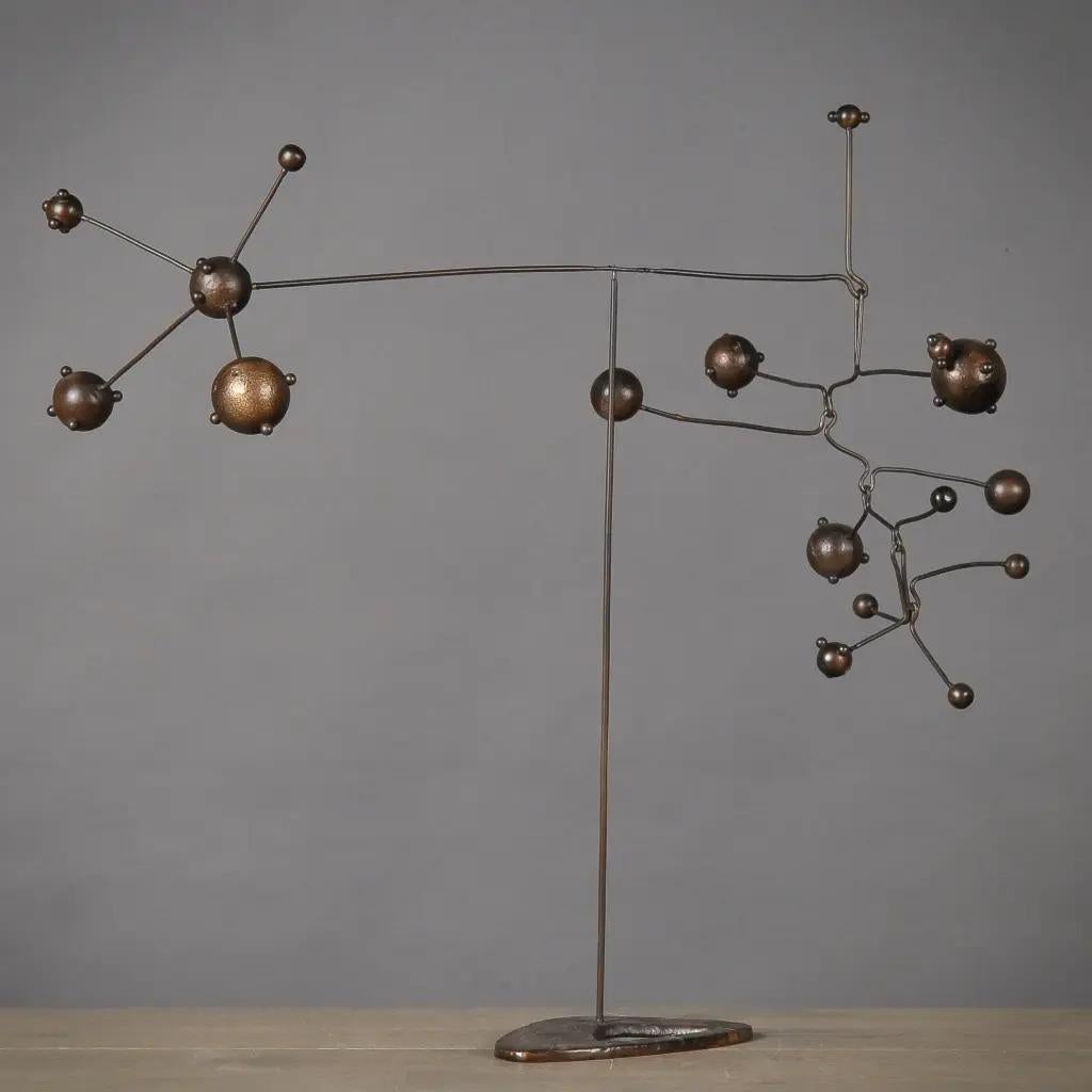 Questo mobile decorativo contemporaneo in metallo evoca l'estetica degli anni '70. Il mobile è costituito da una serie di elementi metallici sospesi che creano un movimento visivo dinamico. Presenta una composizione leggera ed equilibrata, che