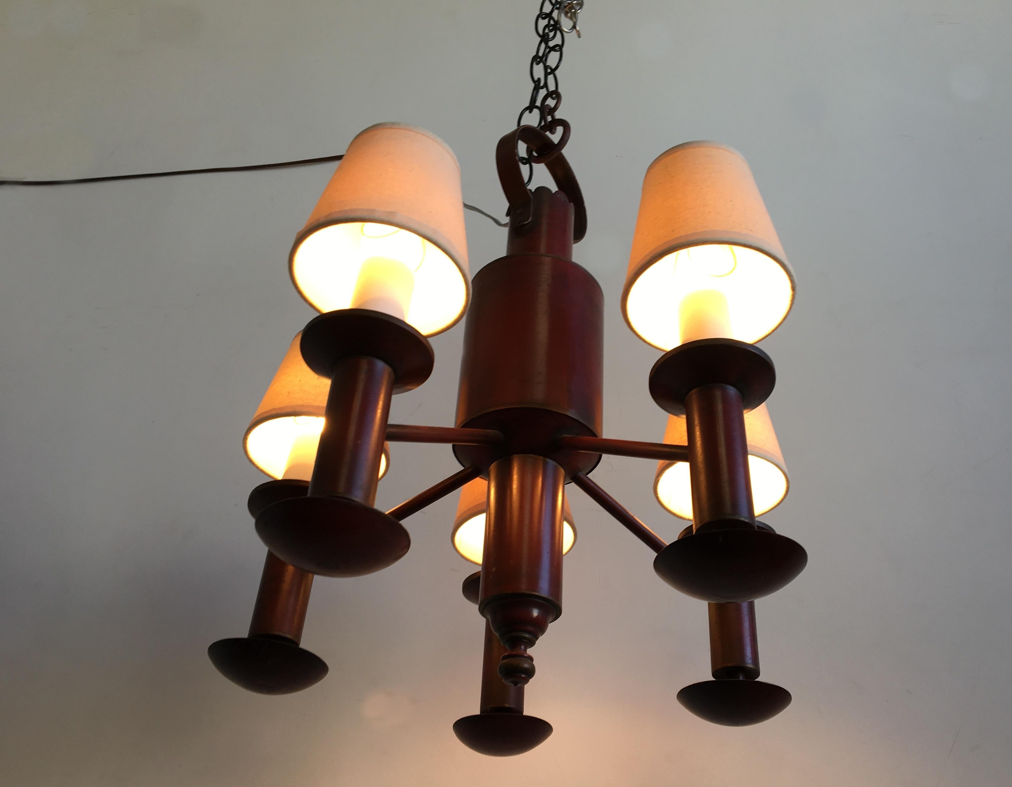 This rustic style chandelier made in the 1940s has a 5-arm candelabra with cream shades. It is made of metal in a deep, brick patinated red color.
It gives a very warm light!
   