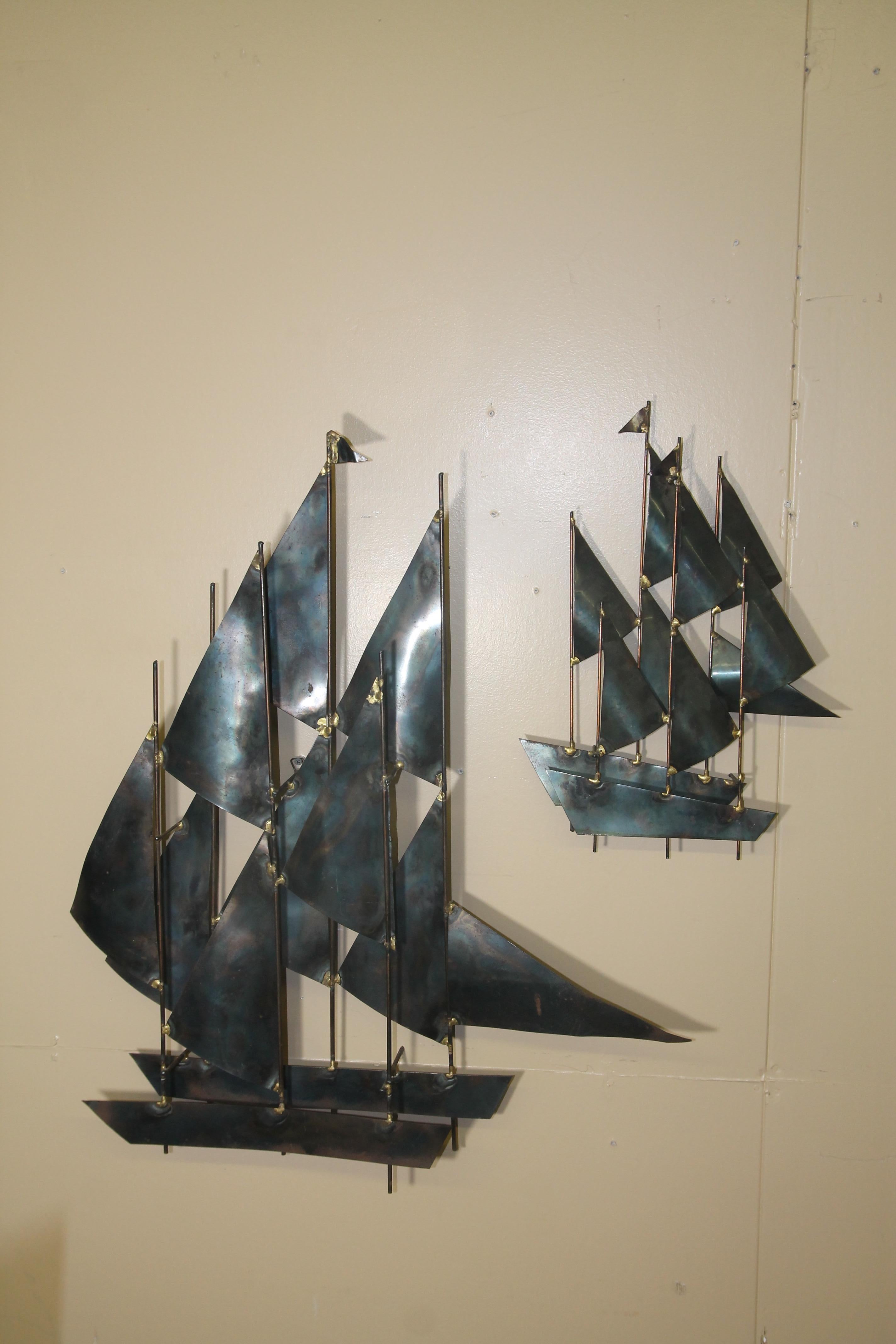 Great pair of metal sailboat wall sculpture in the manner of Curtis Jere. Large ship is 26W x 6D x 32H, small ship is 13.25W x 2.875D x 19H.
   