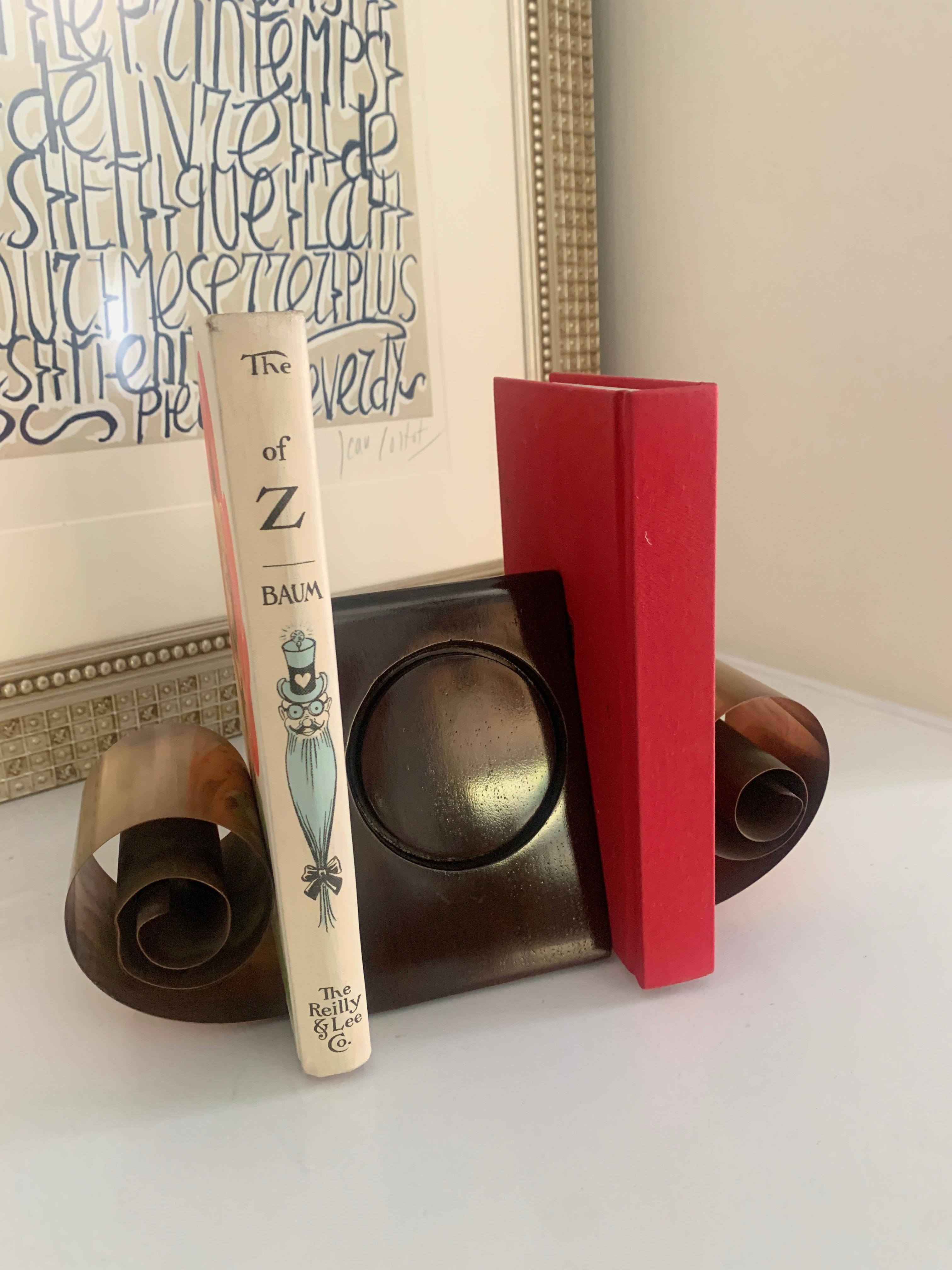 A pair of Metal scroll bookends with center of wood. This unique style bookend is perfectly suited for any desk and especially the Childs room. Pulling back the scrolls allows books to be added and spring style force keeps them neatly in place.