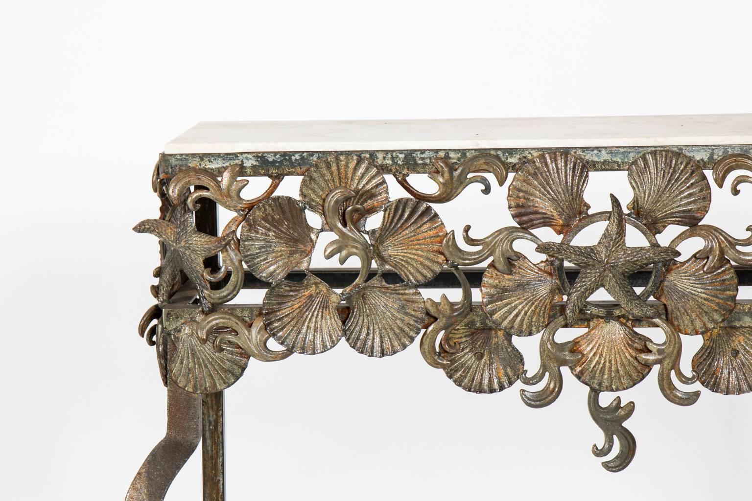 Contemporary glass top console table that features detailed metal scallop shells and a centre starfish on the skirt with cabriole legs.
 