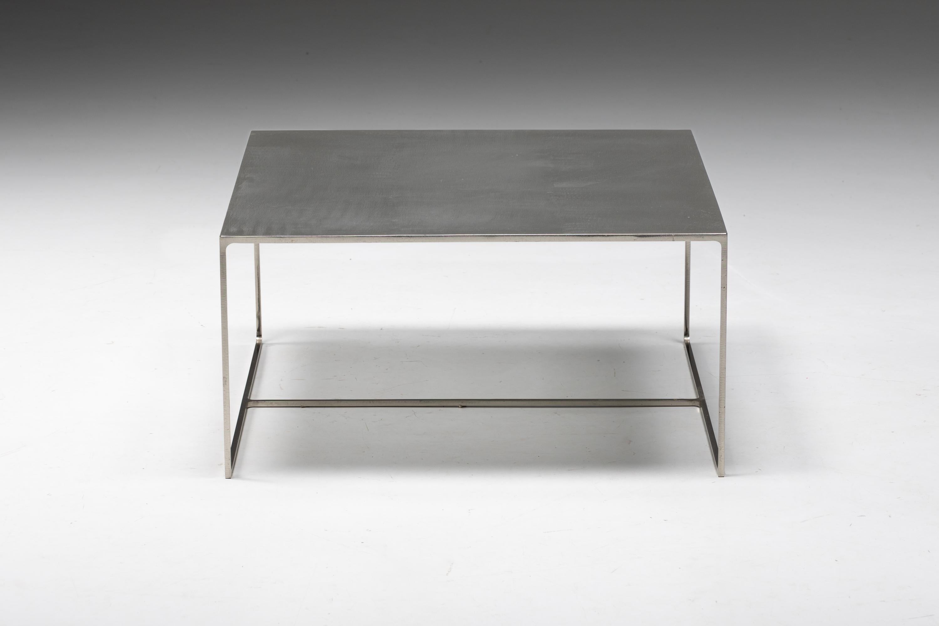Table basse carrée en métal, un meuble remarquable conçu par le visionnaire Rodolfo Dordoni en 1998. Fabriquée avec une attention méticuleuse aux détails, la table basse 'Duchamp' bénéficie d'une solide construction en métal qui respire la