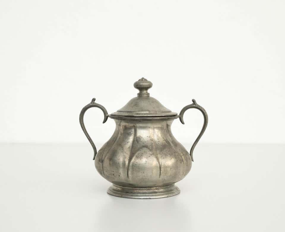 Zuccheriera in metallo, 1920 circa  Prodotto a Barcellona, Spagna.    In condizioni originali, con un'usura coerente con l'età e l'uso, conservando una bella patina.    Materiale:  Metallo    Dimensioni:  H. H. 17,5 cm  L 18 cm  D 13,5 cm.
