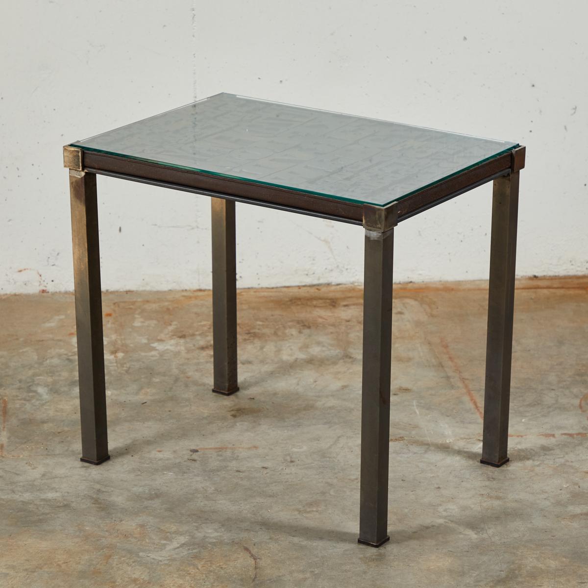 Industrial glass top table with graphic lettered top. The table began its life as a typeface tray in late 19th-century France. Having since been mounted on rectangular iron legs and given a glass top, the table's design reflects its industrial