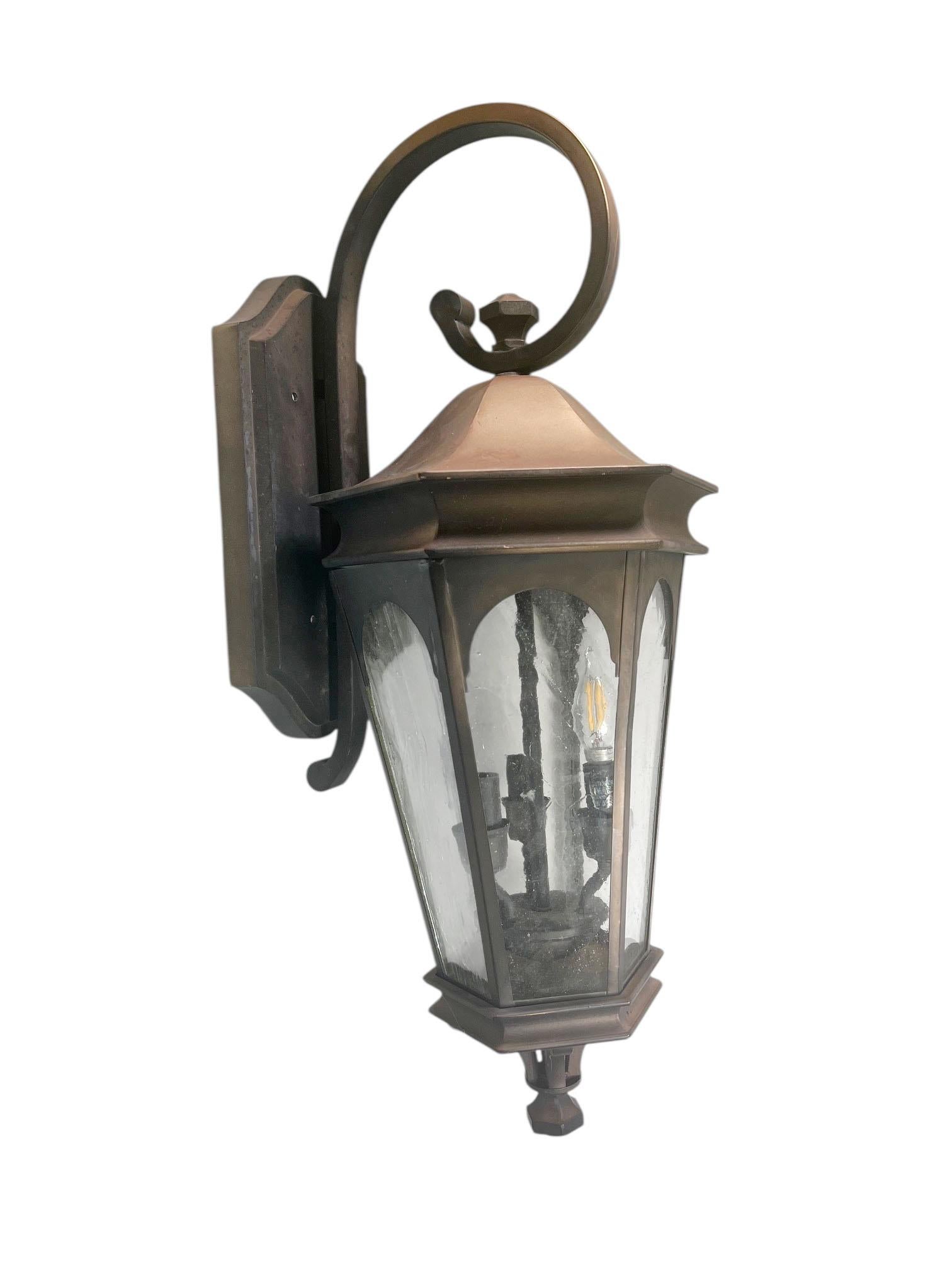 A handsome pair of 20th century metal lanterns, each fitted with three lights and panels of textured crackle glass. The combination of sturdy metalwork and shimmering glass creates a timeless design that blends utility with decorative