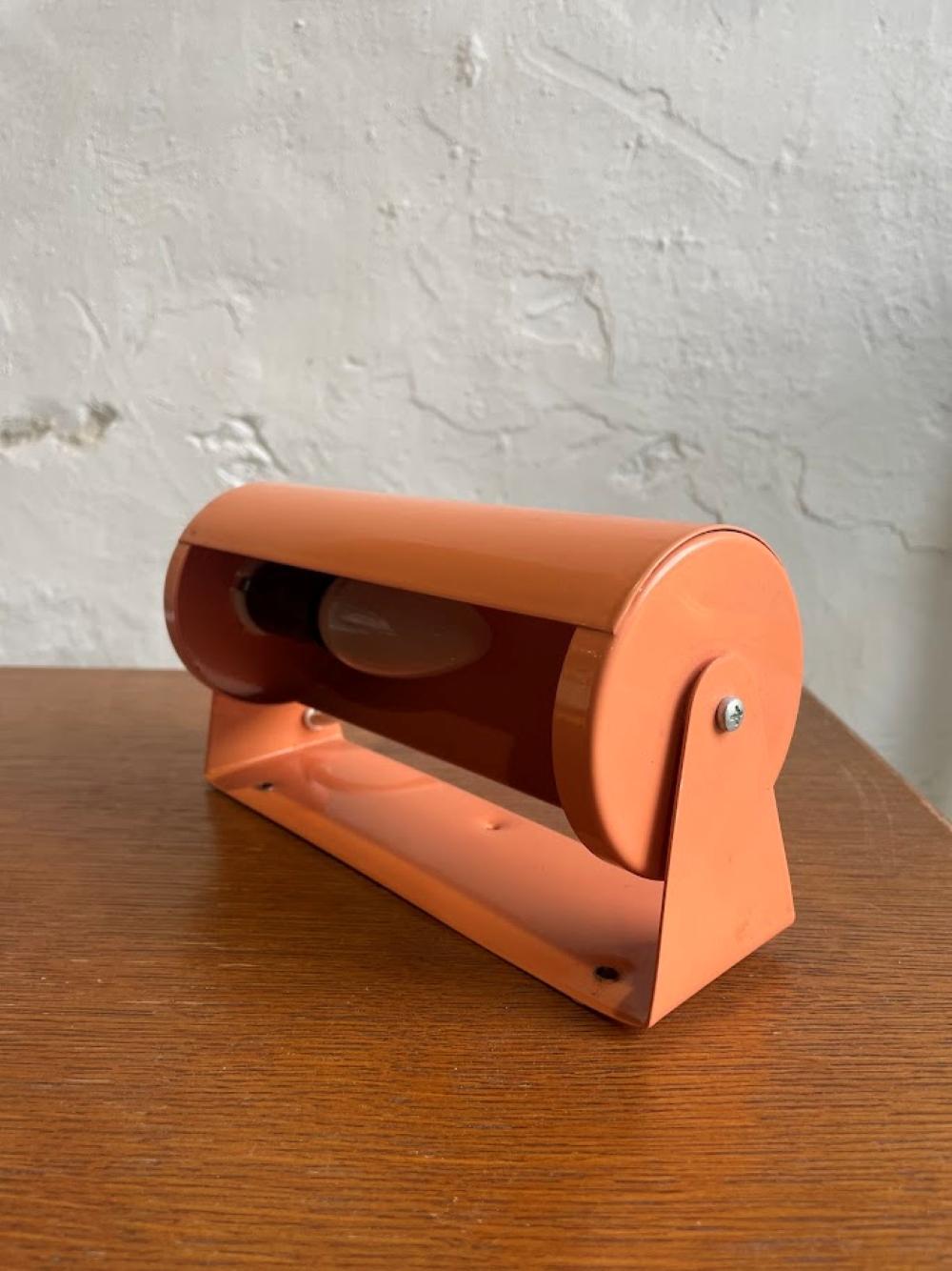 La lámpara de pared Lod V413 fue diseñada y fabricada por IKEA a mediados de la década de 1980 como parte de su colección de iluminación. Este modelo en concreto presenta una distintiva pantalla metálica de color salmón/coral con un brazo ajustable,