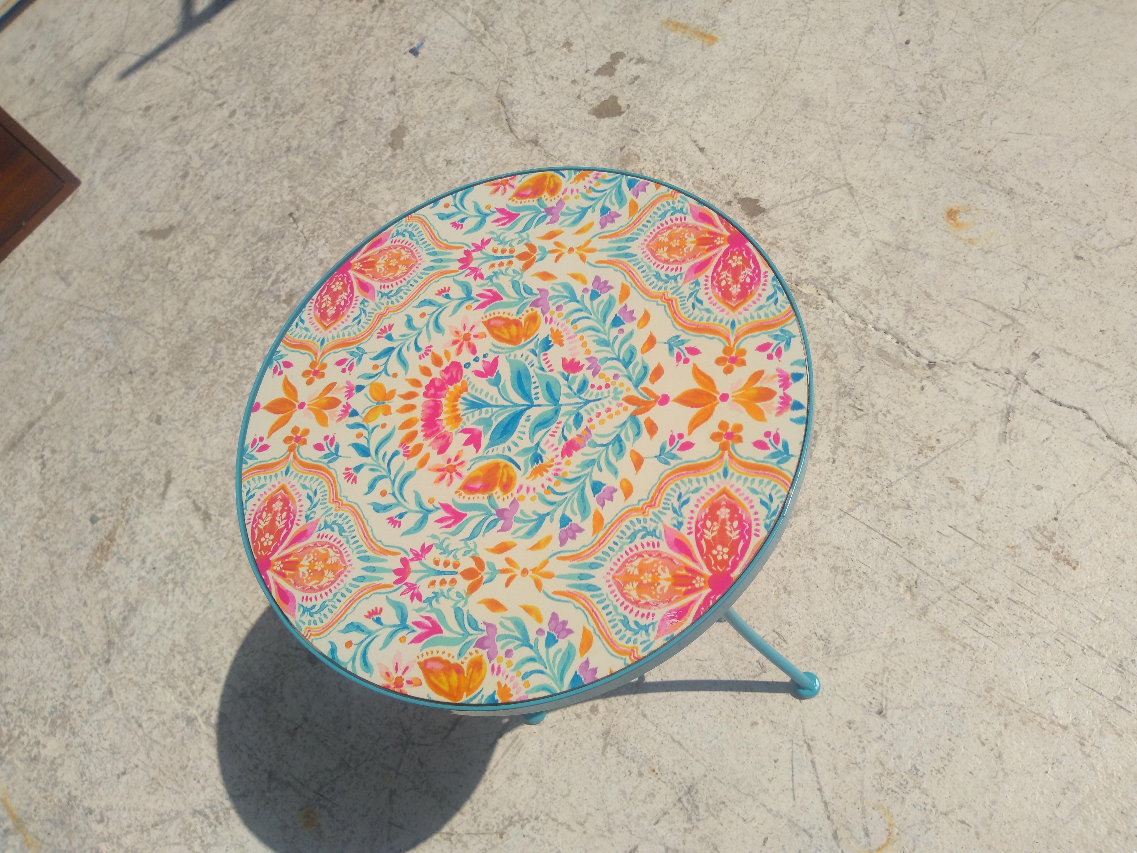 This is a metal pedestal base side table. The tile top makes it an indoor or outdoor table. The top has flowers and butterflies. 