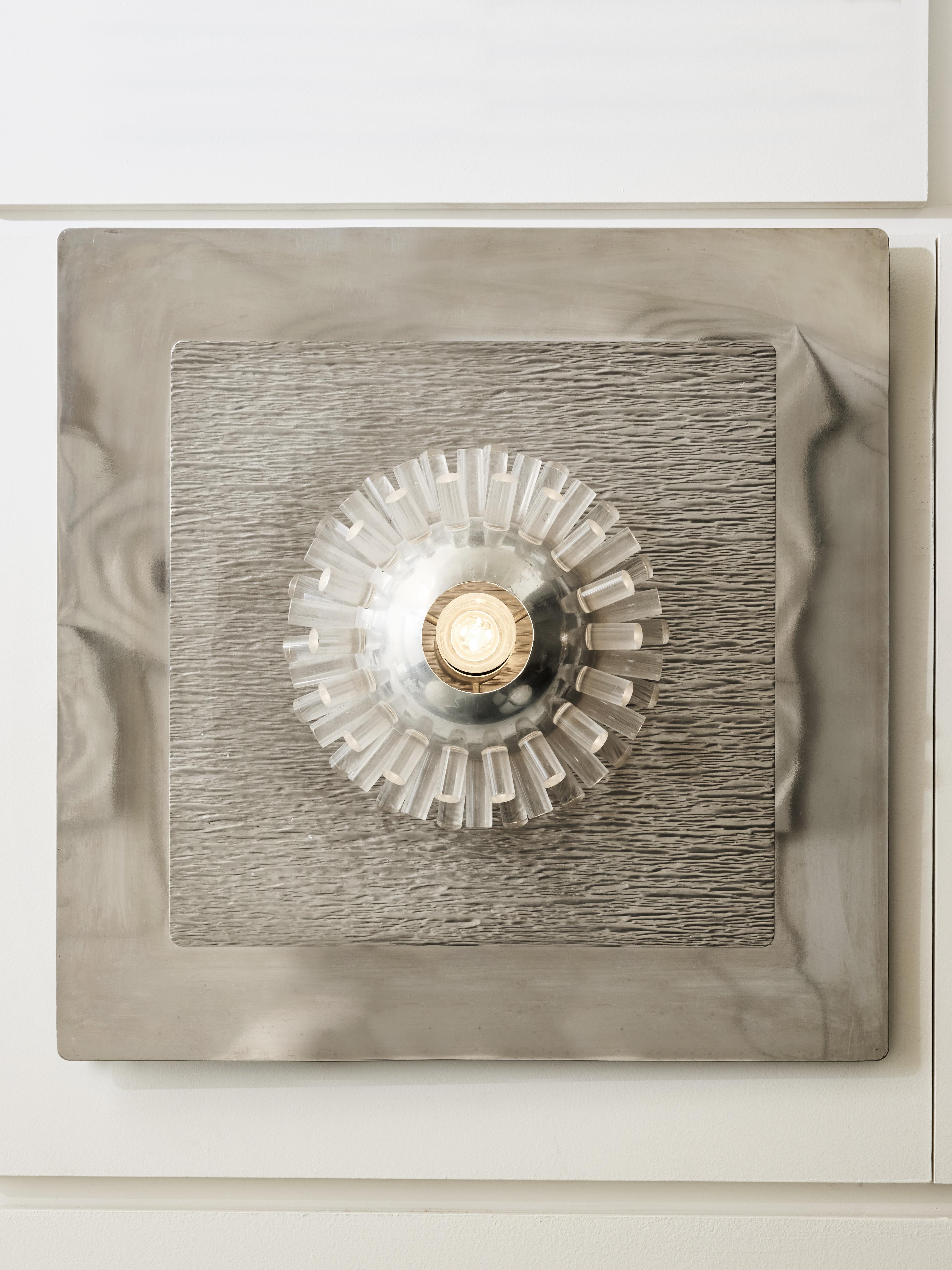 Height panel wall sconces made of a square shiny and reflective metal plate which on top is a mat metal sphere with an opening for the bulb which light bursts through the plexiglass sticks encased in the sphere.

To be installed spaced out for a