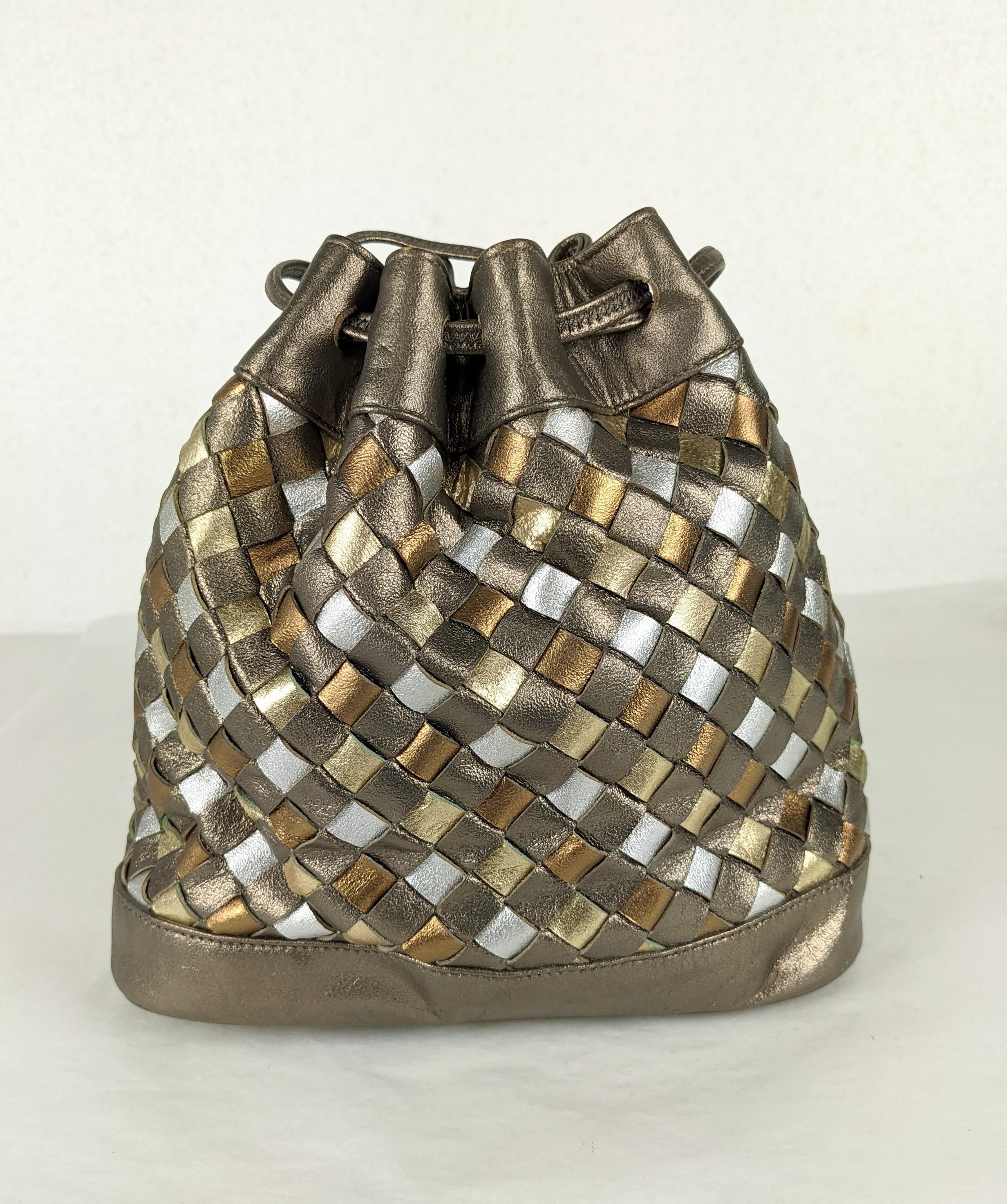 Metallic Leather Woven Shoulder Pouch by Morris Moskowitz. Strips of silver, bronze and and brass toned leather are woven and then formed into a mini drawstring pouch.
1990's USA. Fully lined. 6.5