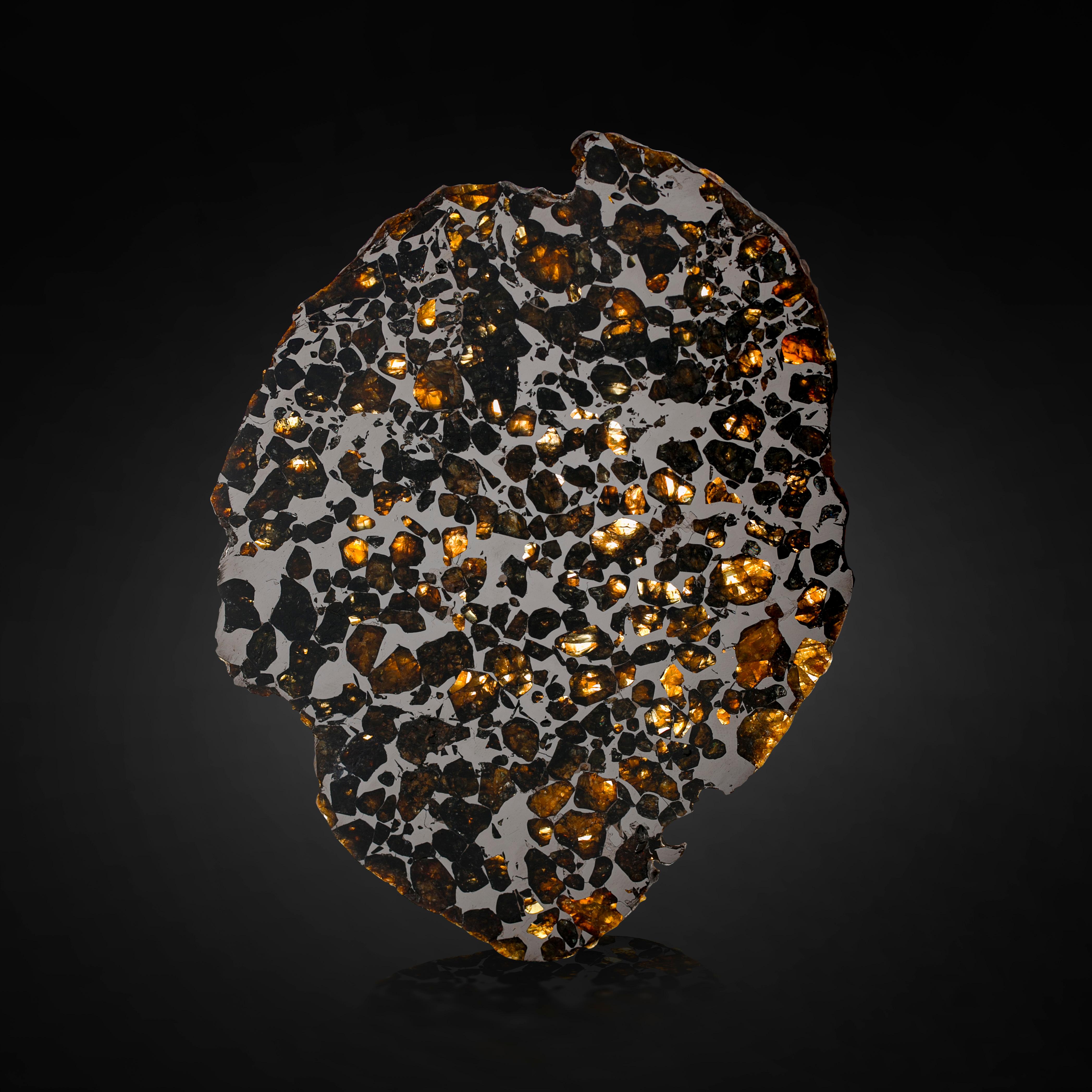 Pallasites are a rare subclass of meteorite that are primarily composed of an iron-nickel matrix (host-rock) and olivine crystals. (Many are familiar with olivine in its gemstone form, peridot.) Only 61 pallasite falls are known to date, with 10