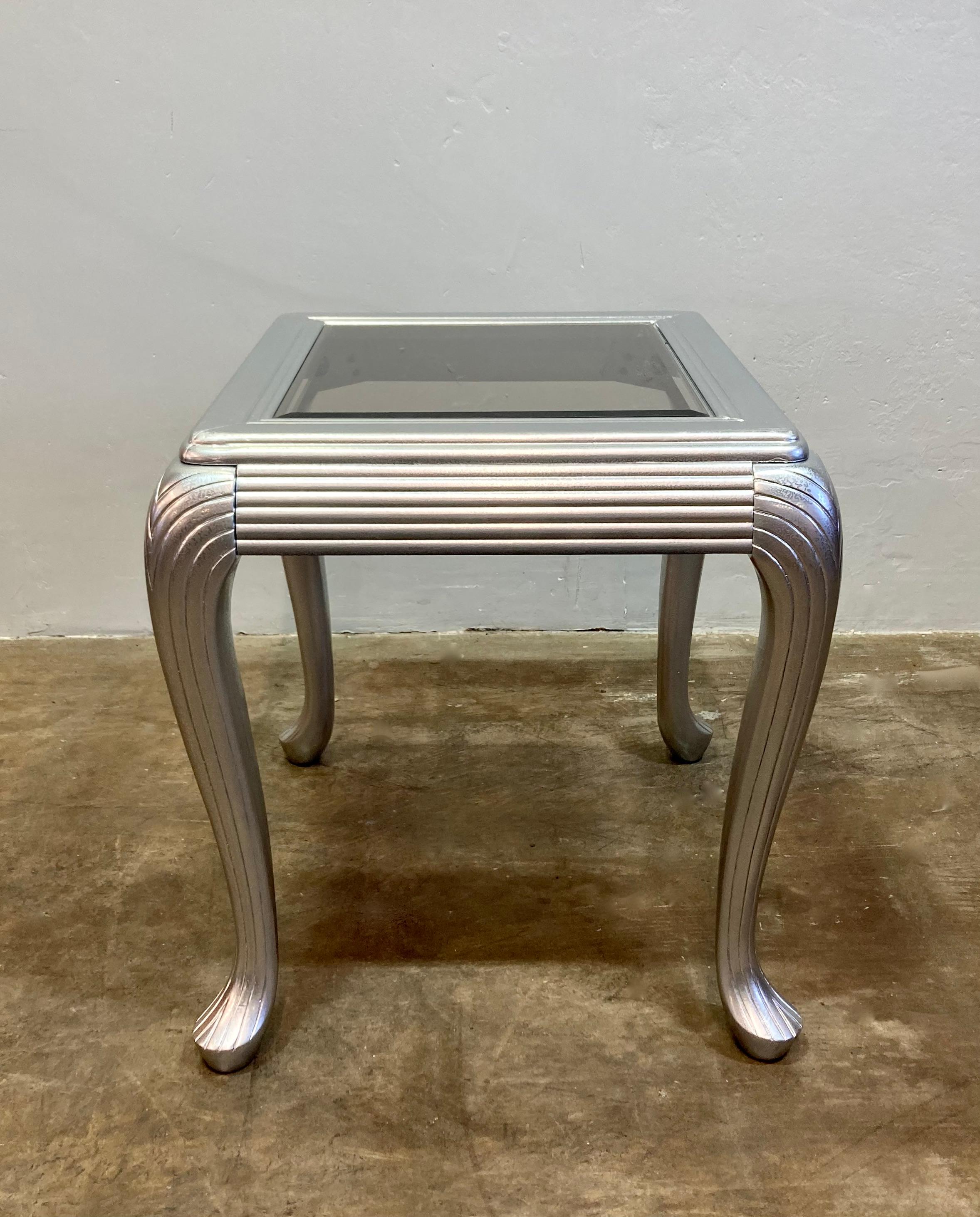 Table d'appoint personnalisée de style art déco. Plateau en verre fumé biseauté, avec cadre en bois fini en argent métallique texturé. Bords en cascade et pieds incurvés de style déco. Une table d'appoint pratique et remarquable, parfaite pour les