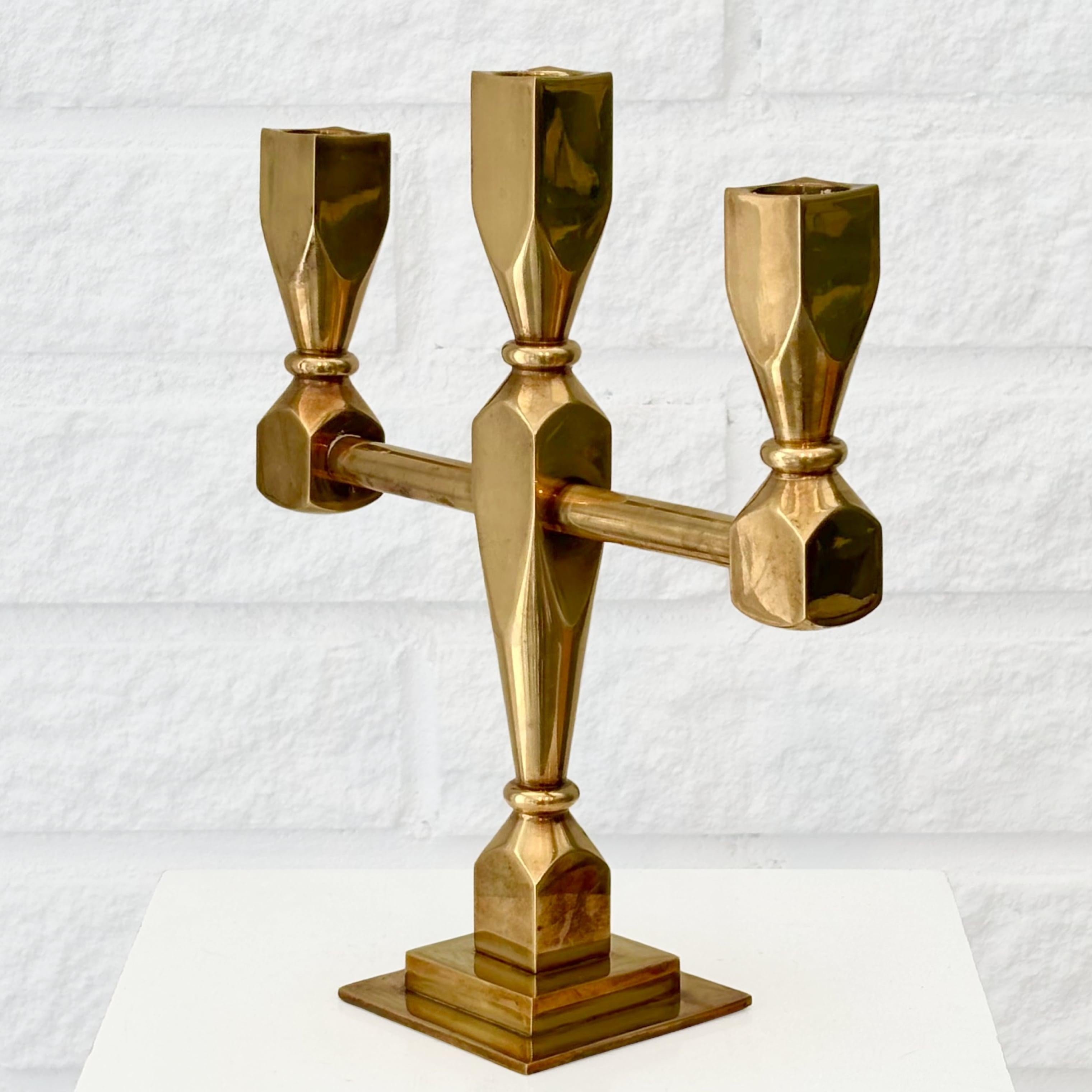 Un candelabro scultoreo della metà del secolo scorso prodotto dal rinomato laboratorio svedese di metalli Metallslöjden Gusum. Caratterizzato da una struttura geometrica pulita con tre portacandele e una base quadrata. Un pezzo consistente che pesa