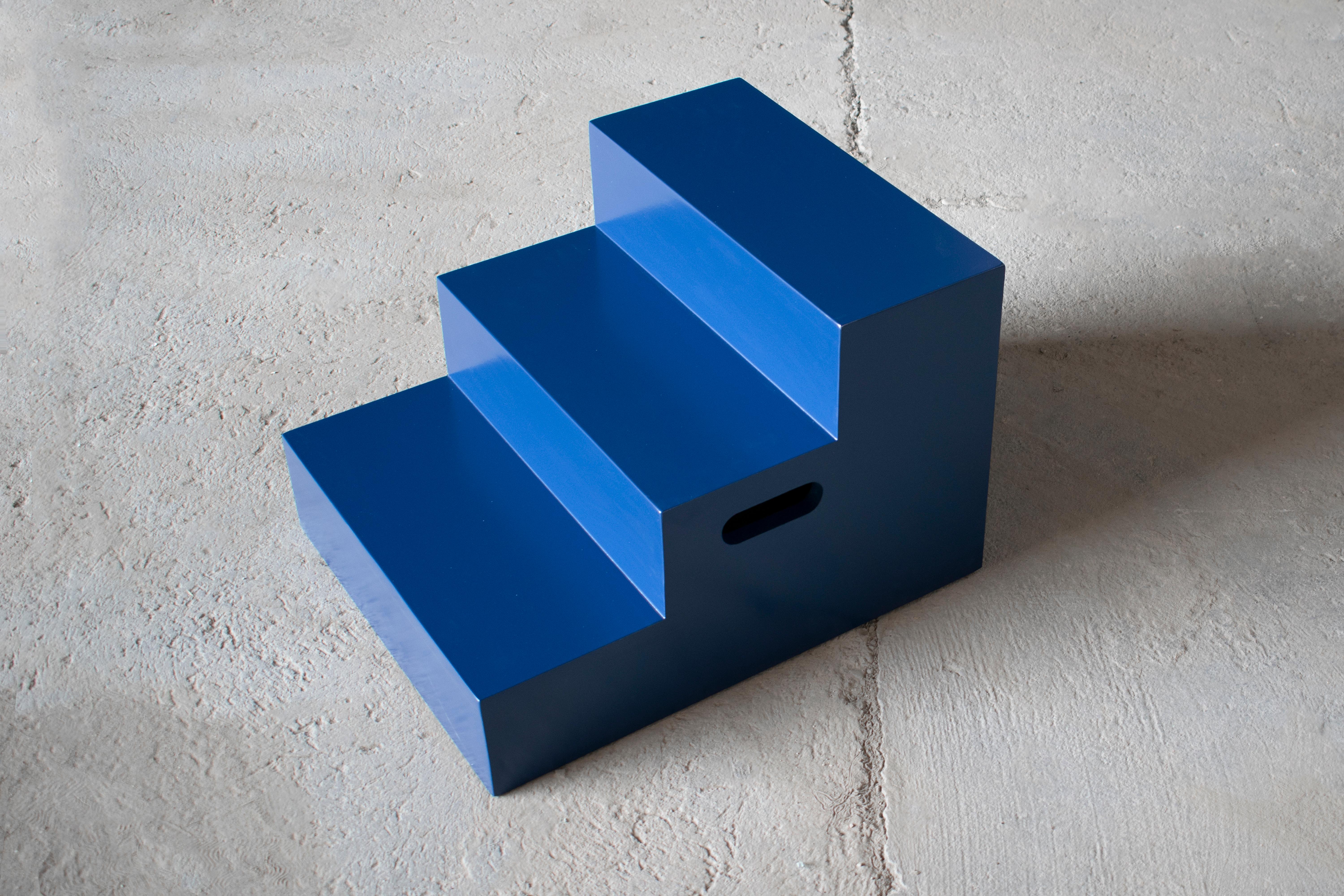 MDF wood lacquered in dark blue colour. 

This design piece is a versatile companion to various functions. Serving as a nightstand, side bed table or stepping surface, the prismatic ladder is a moving furniture ready to be used within larger areas