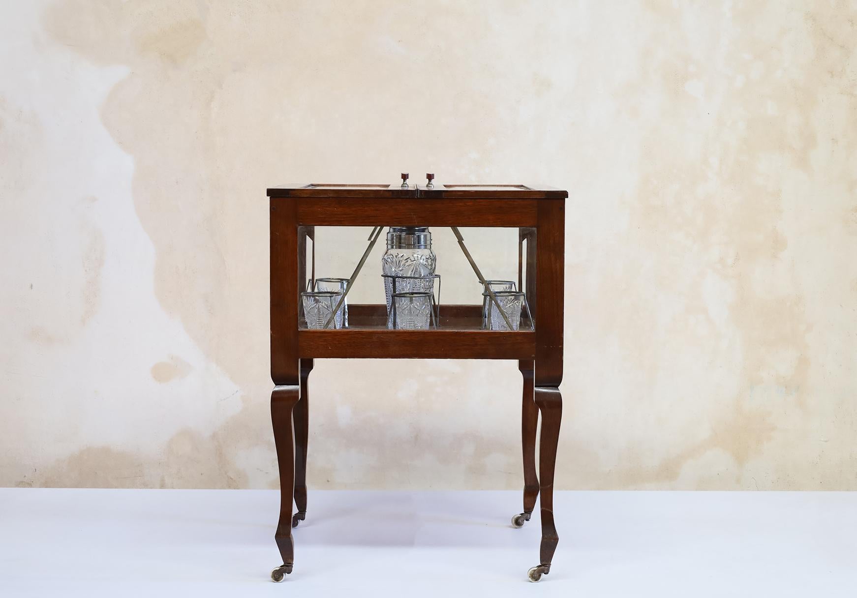 This is a metamorphic oak bar/ cabinet, with a rise and fall mechanism lifting the table top fitted with assorted glassware. circa 1920.
All original.