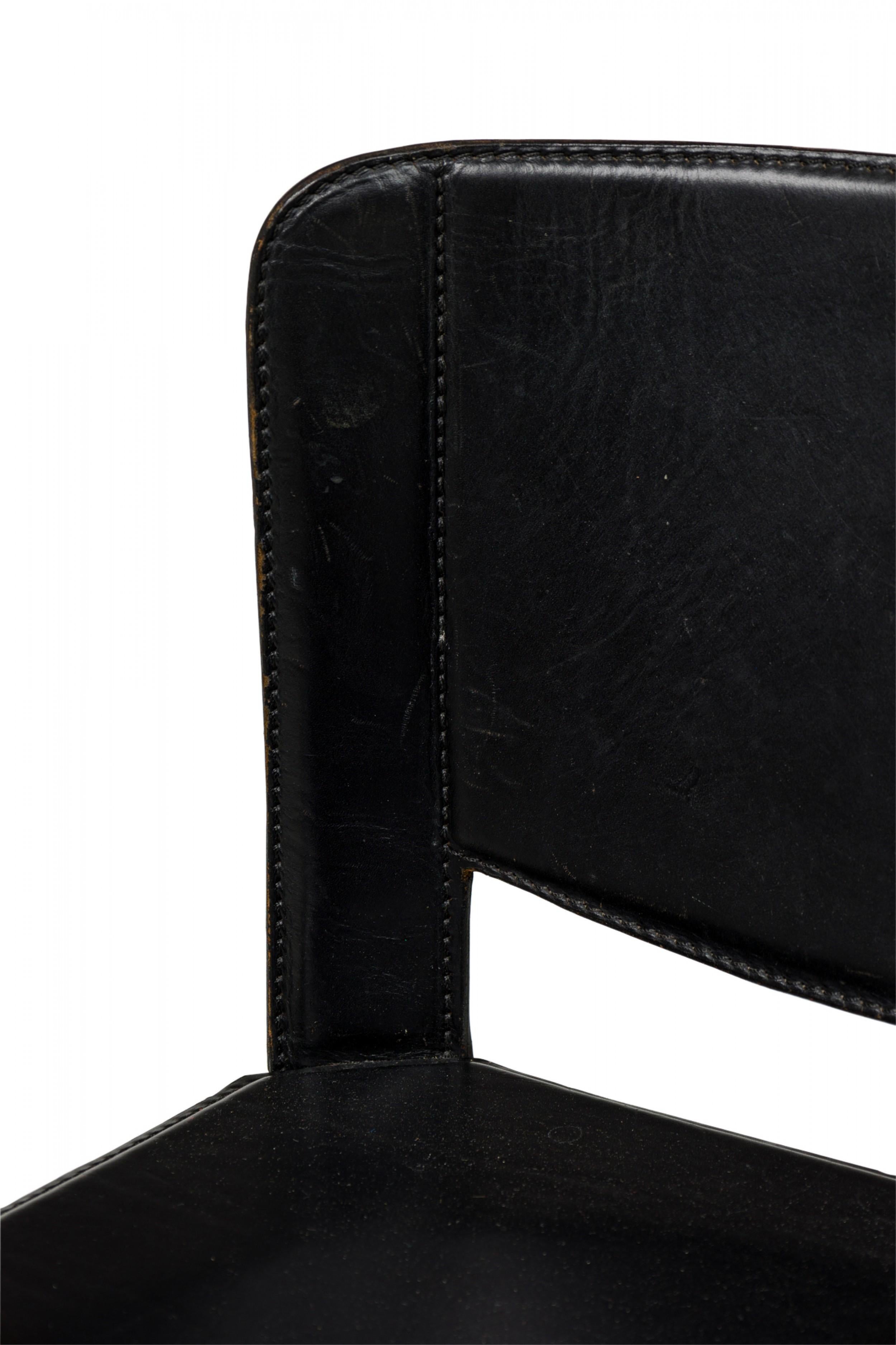 Contemporary Italian (1980s) black leather and wood bar stool with indented seat and curved half-backrest. The seat, base and legs are upholstered in leather stitched and molded to the frame. (METEO GRASSI)

Wear to finish, stitching loose in some