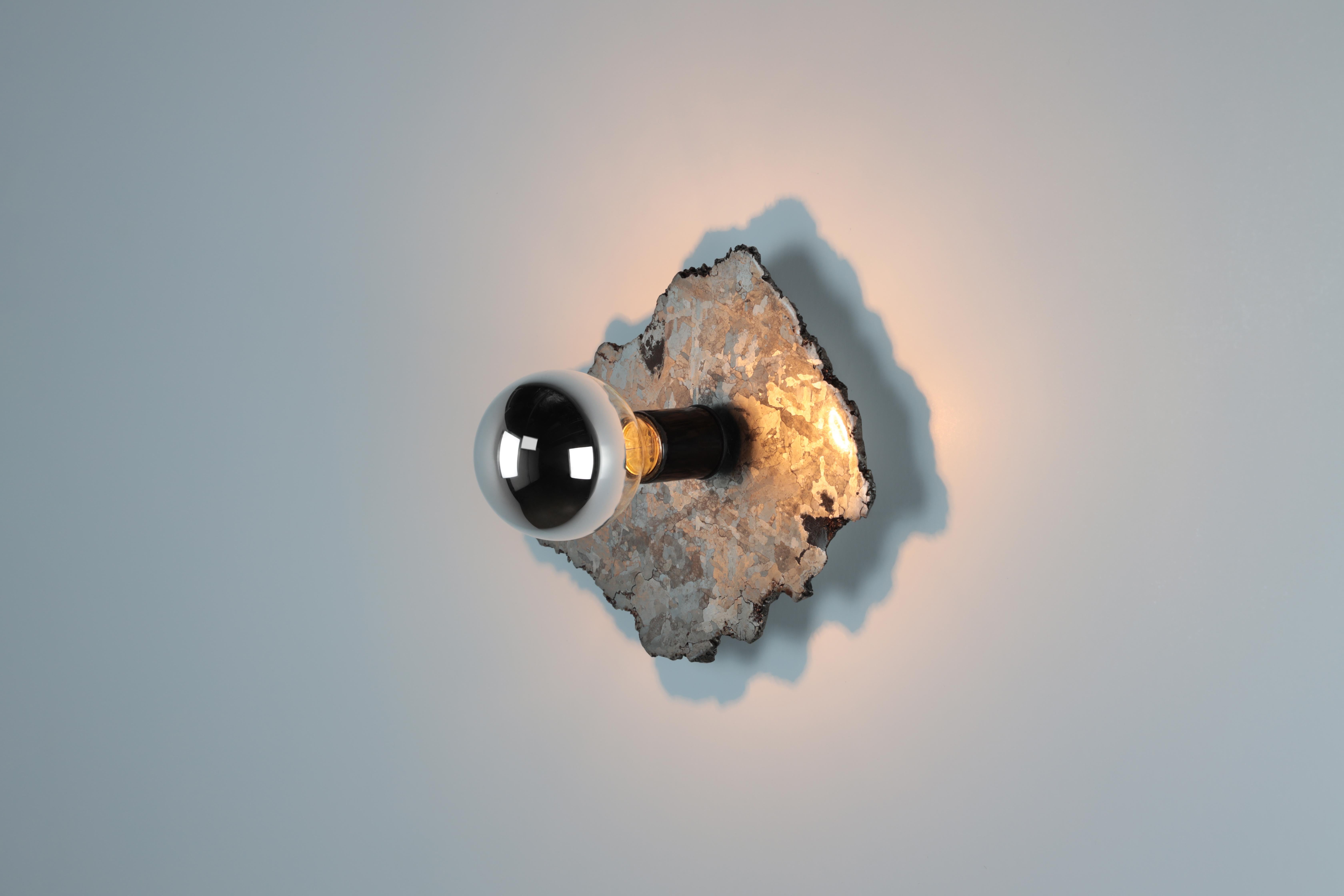 Bring a little piece of outer space into your interior space with this pair of galactic meteorite sconces.
A large meteorite dated 5500 years old was cross sectioned and polished. The fixture comes with a pair of half chromed medium socket halogen