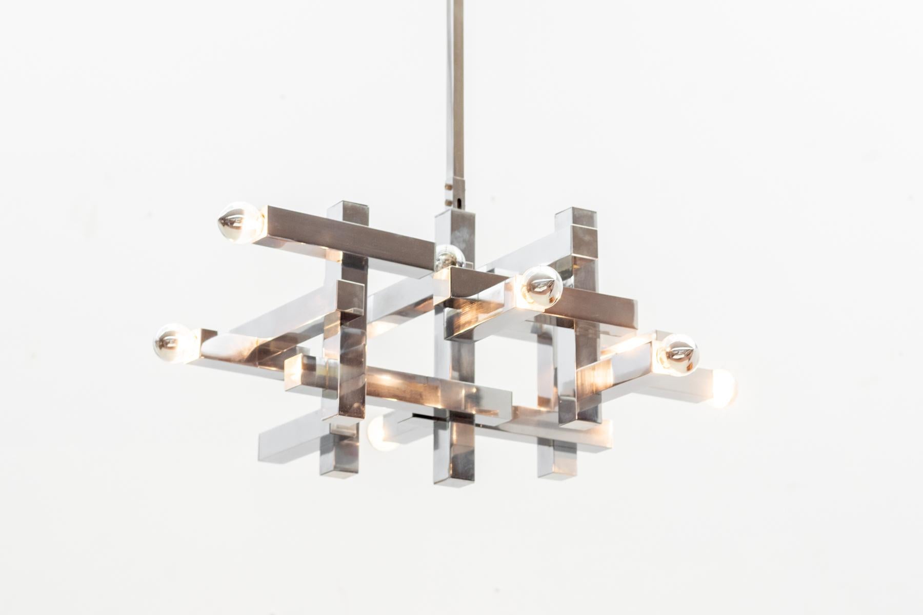 Gaetano Sciolari's Metric chandelier is characterized by its clean lines and geometric precision. The luminaire features a structured frame in polished chrome, creating a harmonious interplay of straight and angular elements.

Adjustable height on