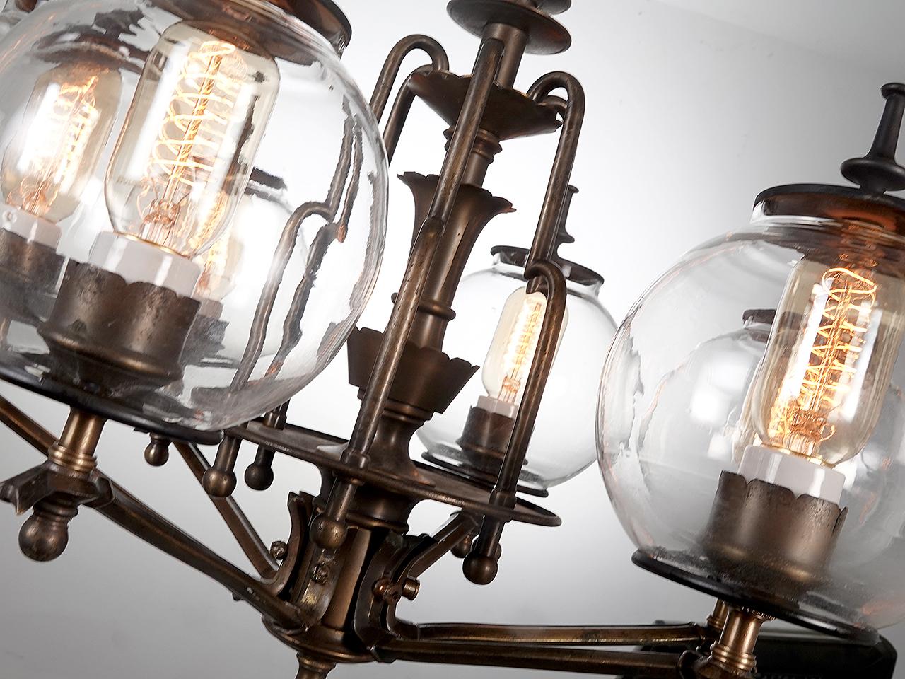 We have 2 of these high style Deco lamps in stock. They are priced per lamp. I can't help but think of the movie Metropolis when I look at this lamps details. Each lamp has six, 6 inch clear capped globes. The clear globes add to the chandeliers