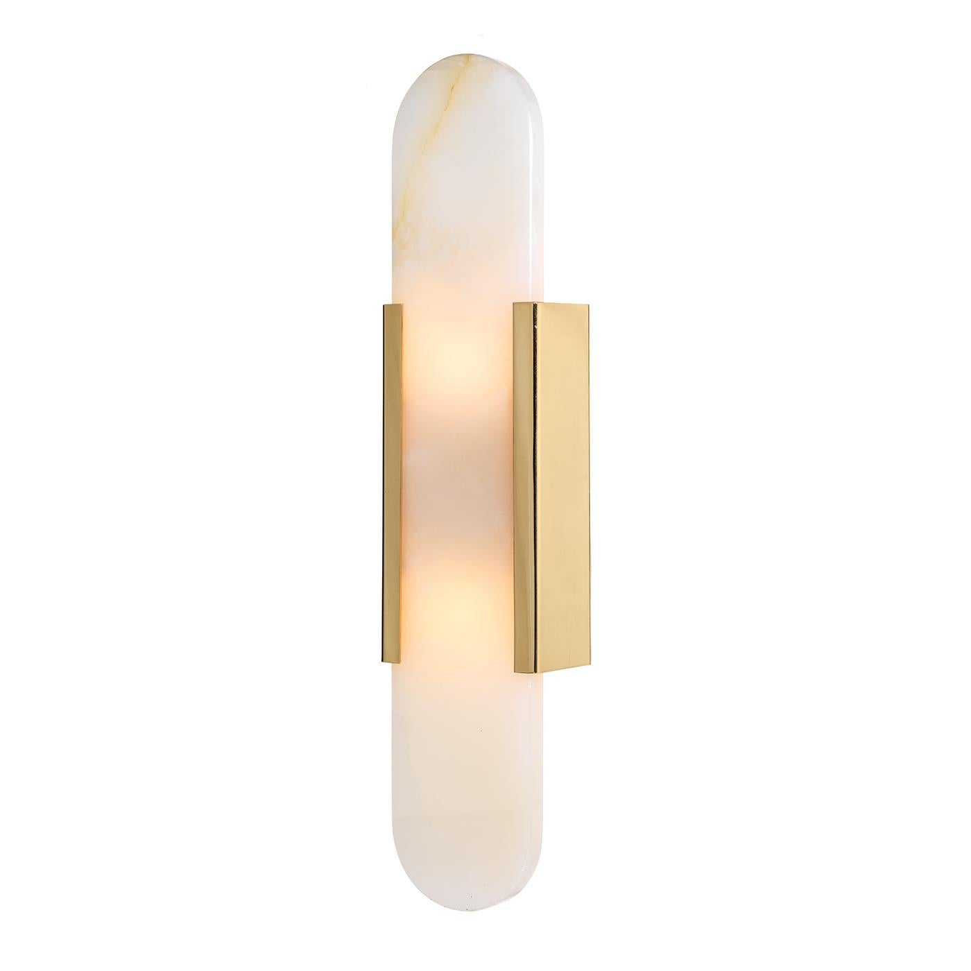 This elegant and minimalist wall lamp is best displayed as a set of two to light up a modern hallway or living space. Its simple and luminous brass frame holds an elongated onyx slab with rounded extremities, resulting enchantingly emphasized in its