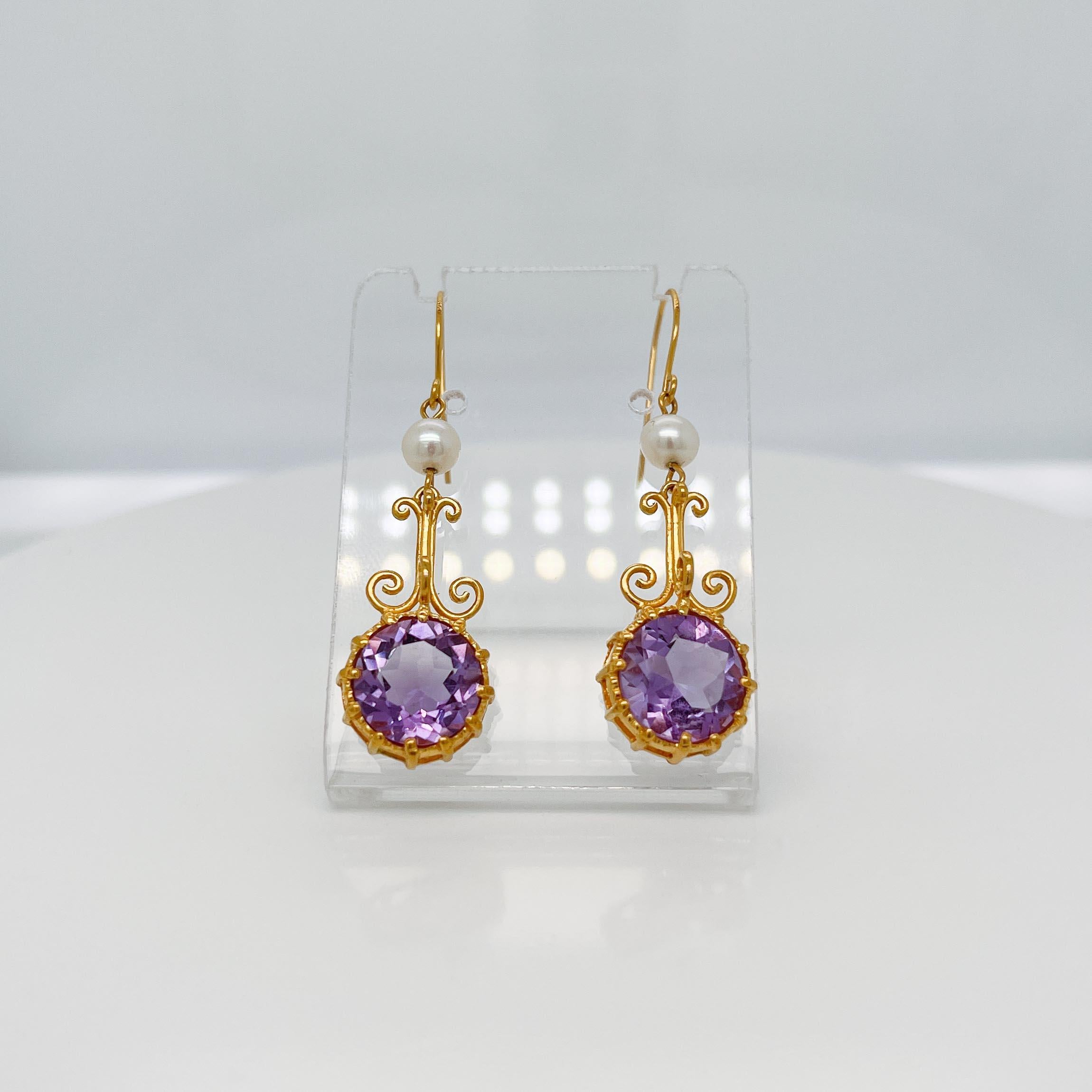 A very fine pair of earrings from the Metropolitan Museum of Art.

In satin finished 14k yellow gold . 

Each earring prong set with a round faceted amethyst gemstone suspened below around white pearl and ear hook.

The gold has a satin finish