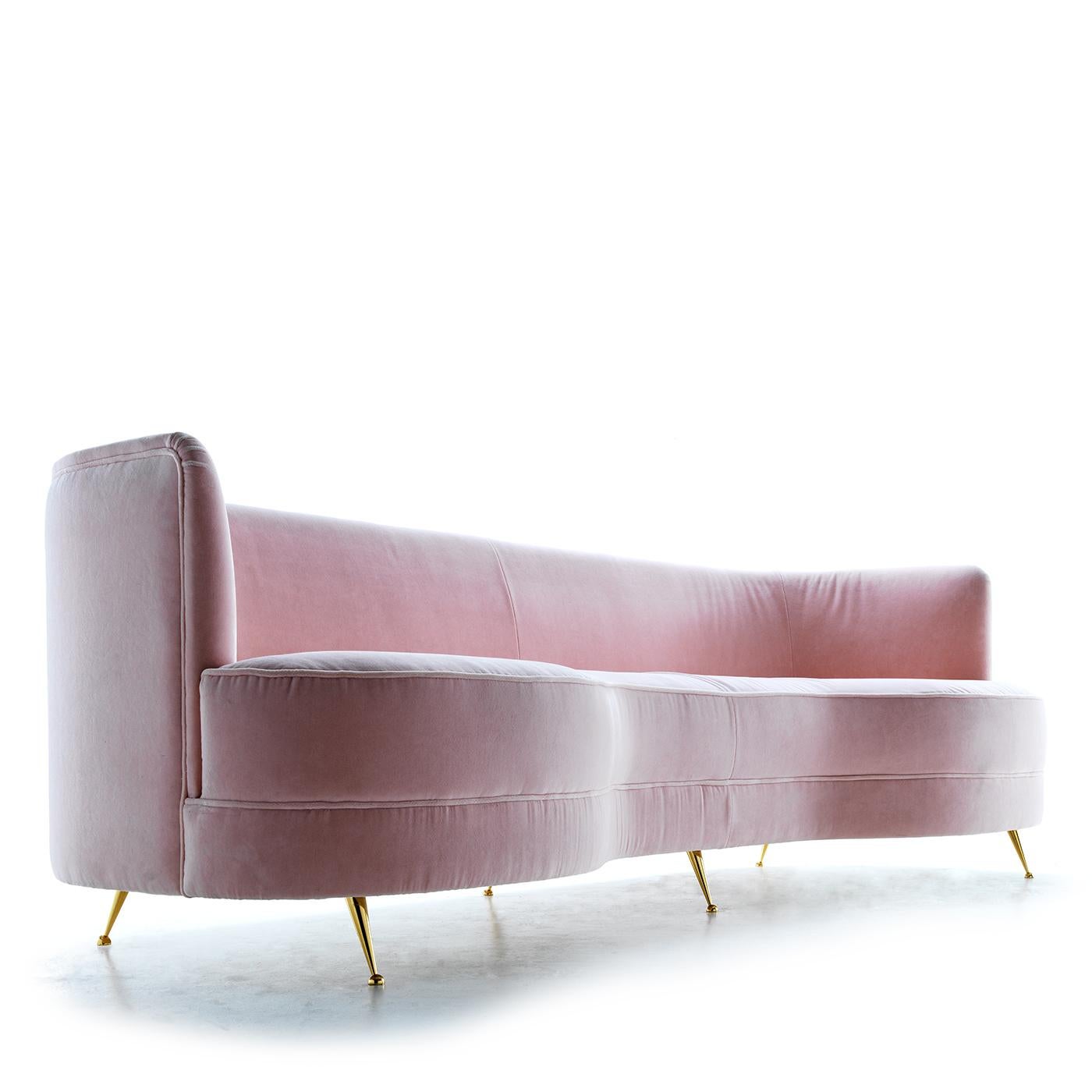 Channeling a seductive feminine flair, this sofa strikes with its soft curves and glamorous aesthetic. Its embracing shape pairs well with the comfortable velvet upholstery in pastel pink, covering the generous padding underneath that makes the