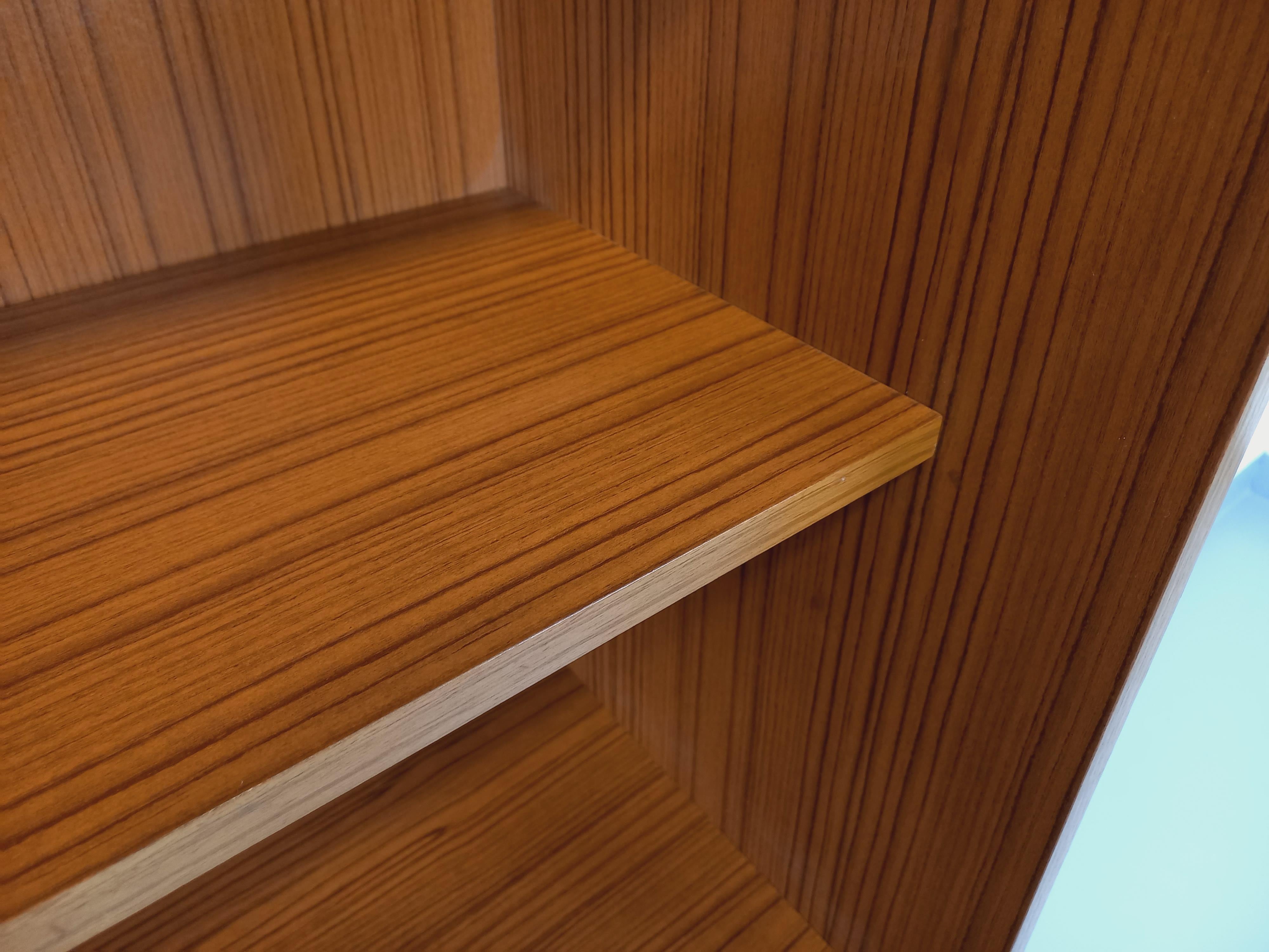 Meuble bibliothèque de rangement vintage style scandinave des années 60, en mélaminé esprit teck, jolie poignée en teck, 2 étagères ouvertes en partie haute, 2 portes en partie basse, très bon état général avec quelques signes du temps qui