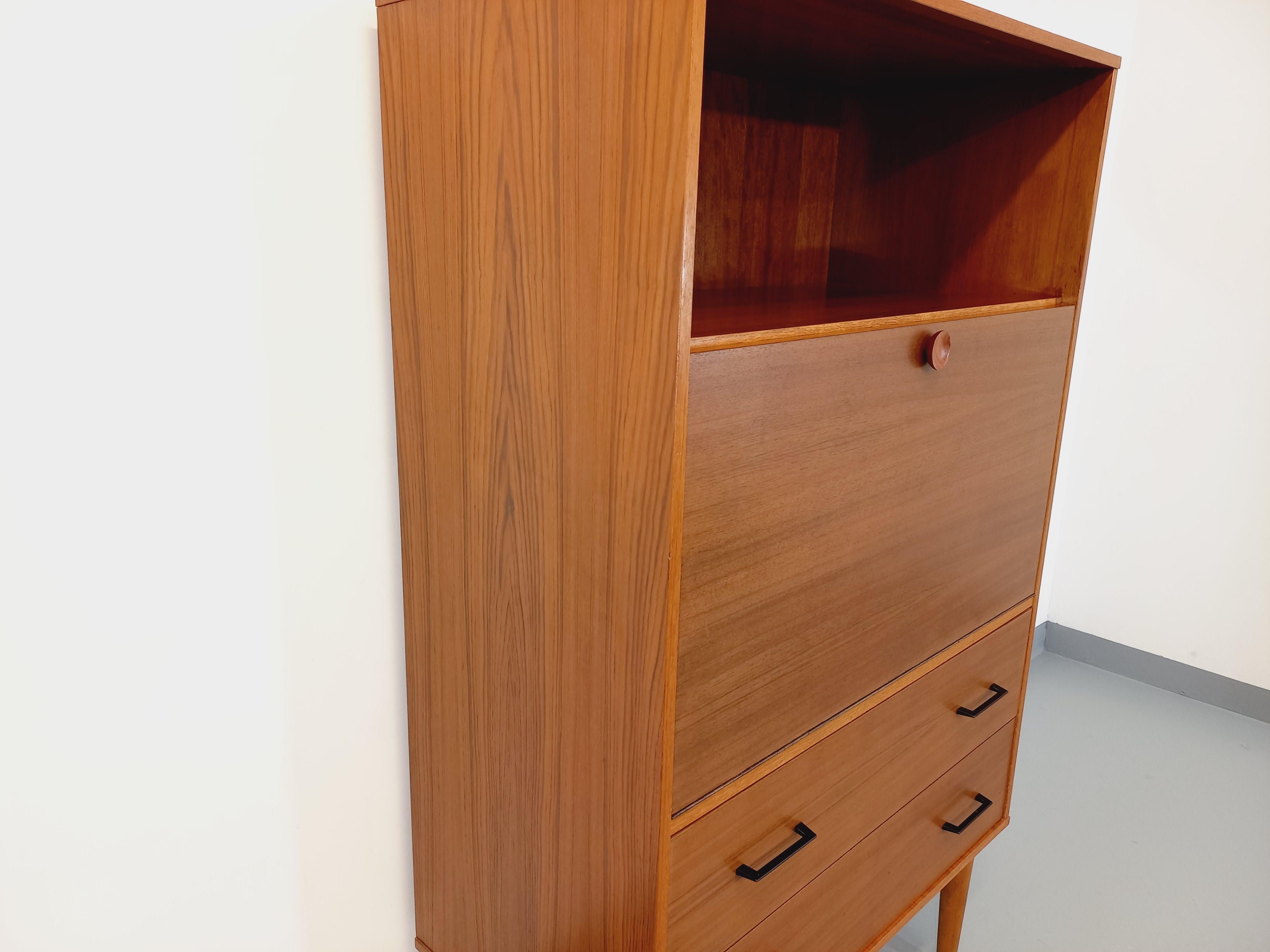 Meuble secrétaire vintage des années 50 60, en teck, pieds compas. Vieles: 1 offene Nische, 1 Sekretär/Büro mit einer hübschen Teckdecke und einer kleinen Innenetage, 2 große Kacheln im unteren Teil mit Decken aus schwarzem Metall. Très bon état