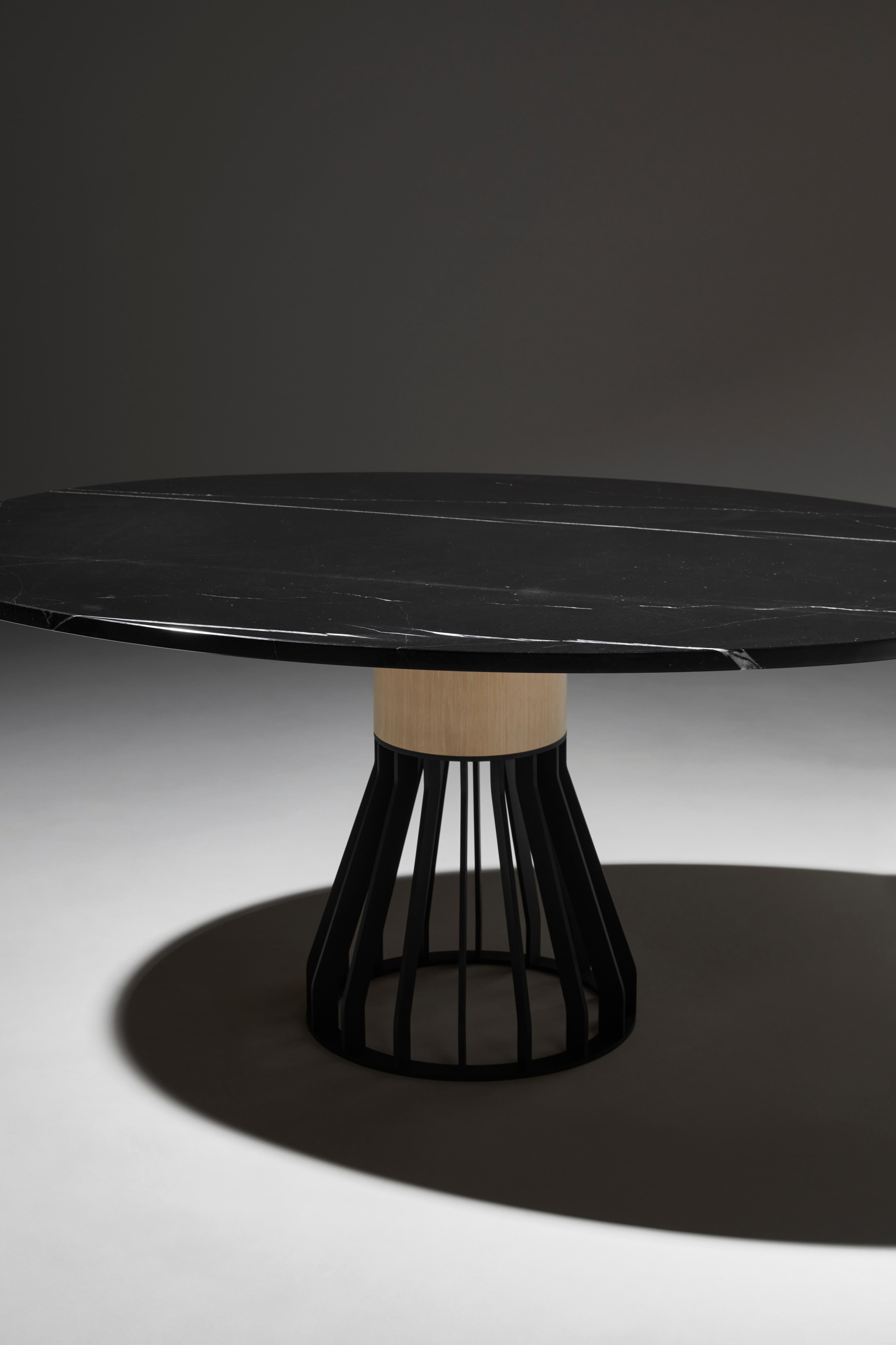 Mewoma is a family of tables with a sculptural presence.
The table combines a laser cut metal base topped by a large wooden column supporting the marble top.
The three materials gave the table its name : metal (ME), wood (WO) and marble