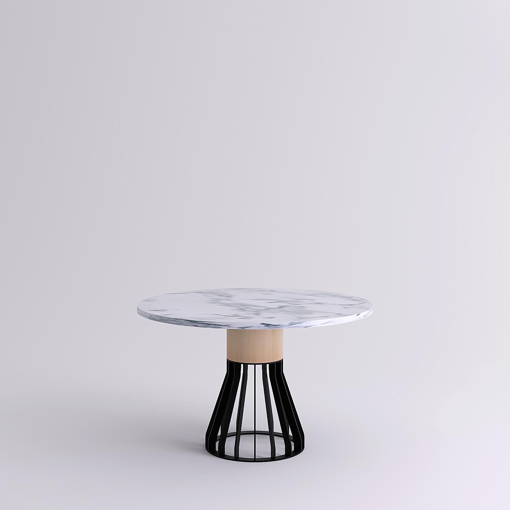 Mewoma is a family of tables with a sculptural presence.
The table combines a laser cut metal base topped by a large wooden column supporting the marble top.
The three materials gave the table its name : metal (ME), wood (WO) and marble