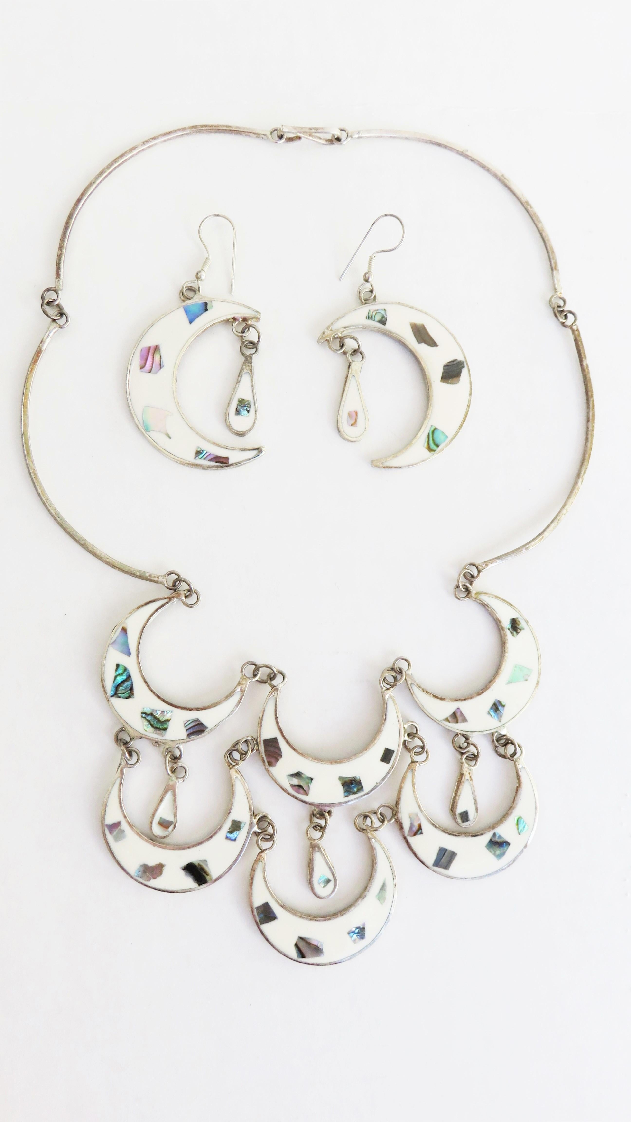 A very pretty necklace and earring set with inlaid abalone in white enamel.  There are 6 white enamel abalone inlaid crescents and 3 tear drops comprising the front bib of the necklace connected by bar links with a back hook closure.

Necklace