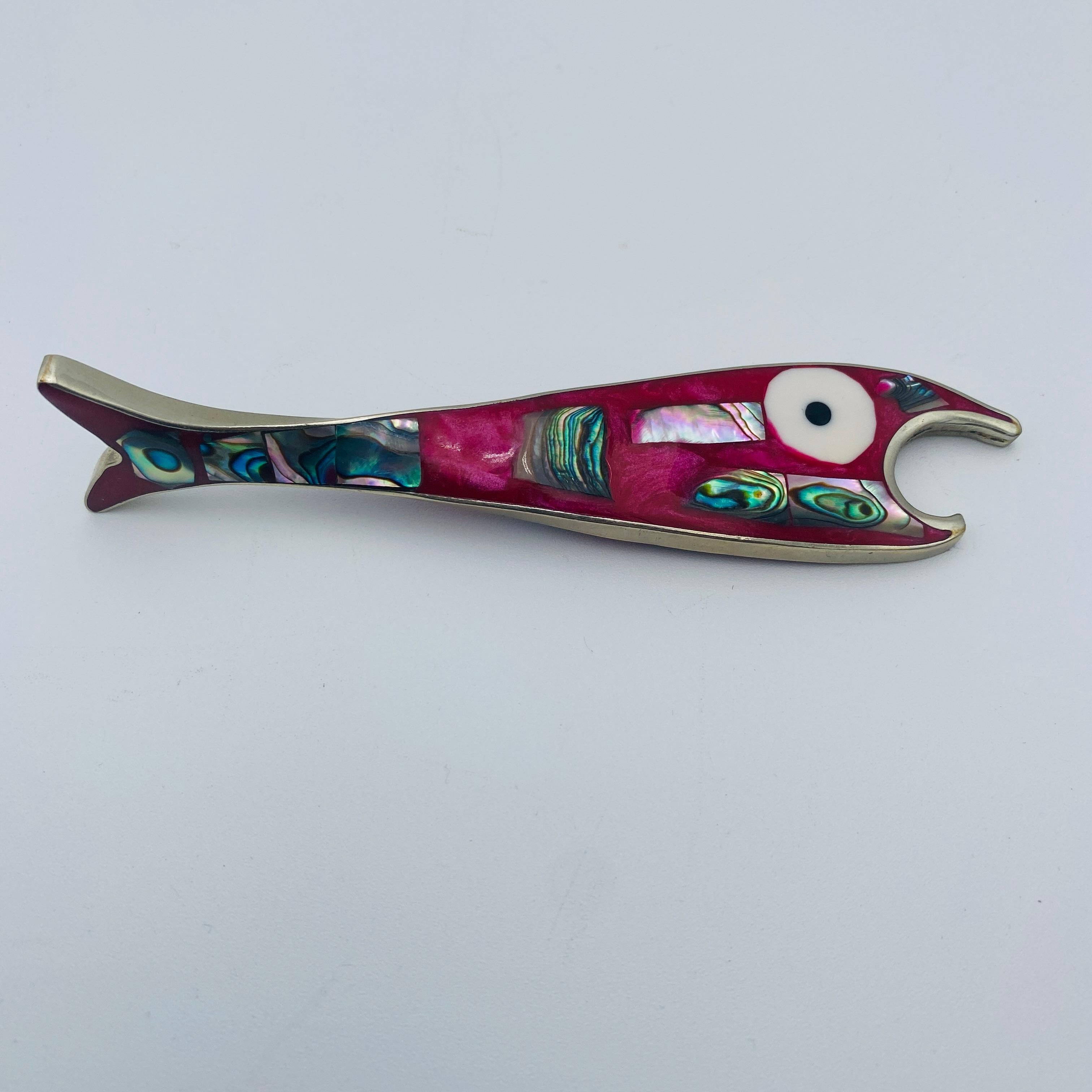 Se trata de un abrebotellas de pescado con incrustaciones de abulón y plata de alpaca de colores, fabricado en México. Es una hermosa pieza para tu bar, especialmente uno con influencia moderna de mediados de siglo. Es a la vez decorativo y