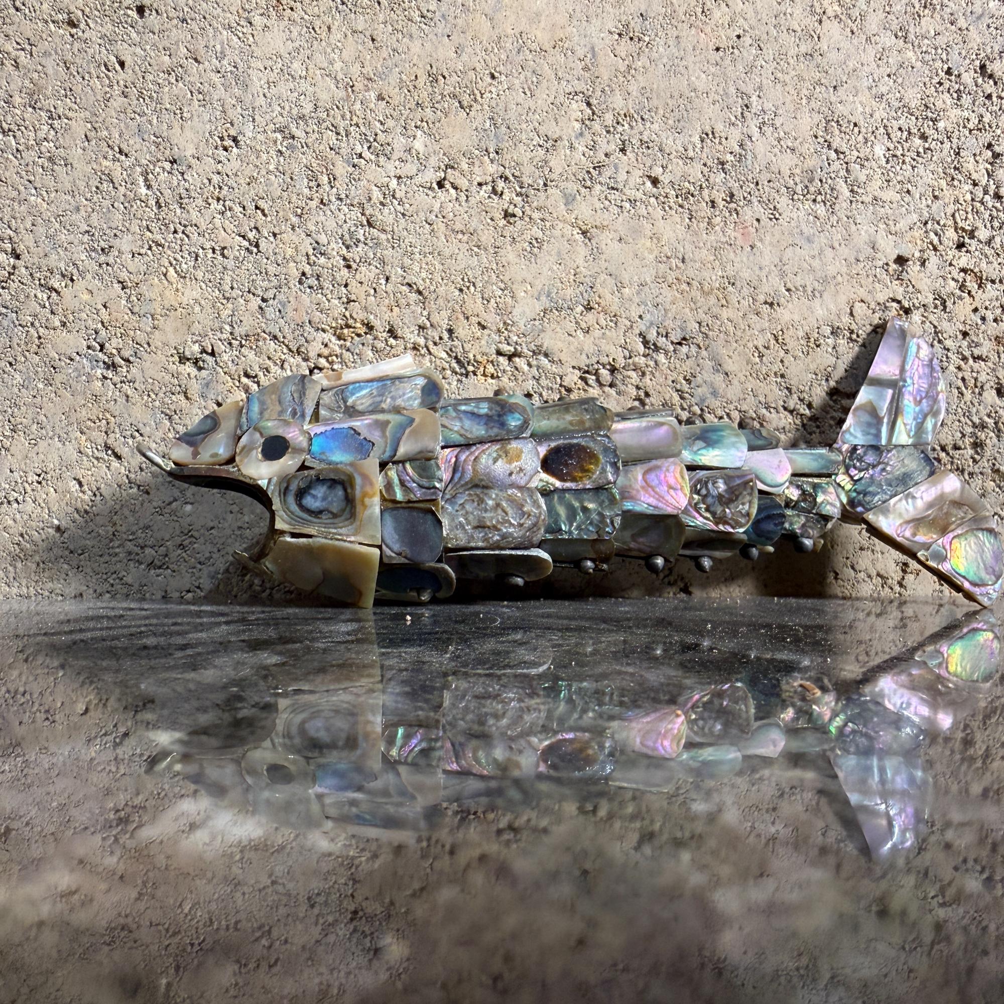 For your consideration, a vintage Mexican articulated fish bottle opener made with abalone shell in the style of Los Castillo. Unmarked.
The body is segmented and articulated, allowing it to bend. 
It is crafted from abalone shell pieces and metal,