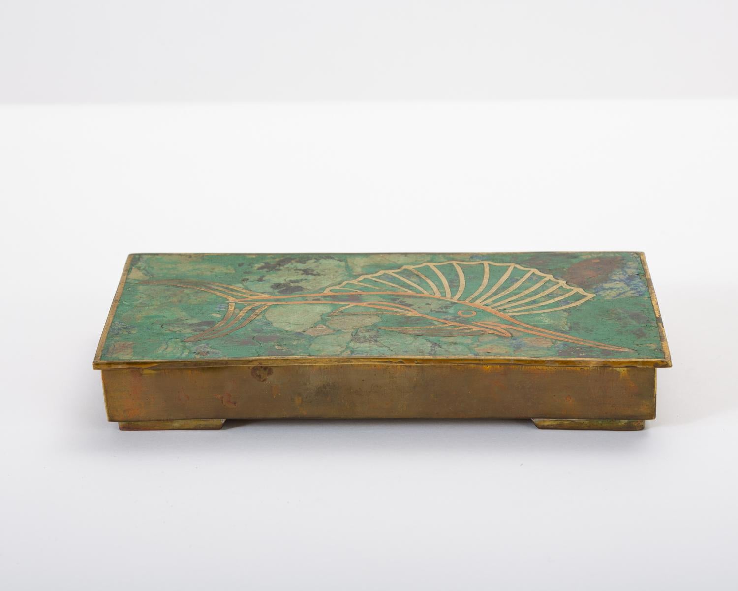 A modern interpretation of cloisonné technique after the designs of José Mendoza for Pepe Mendoza. The brass box has a sailfish design on lid with a brass border, with a vitreous enamel in marbled green and gold tones. Interior compartment is