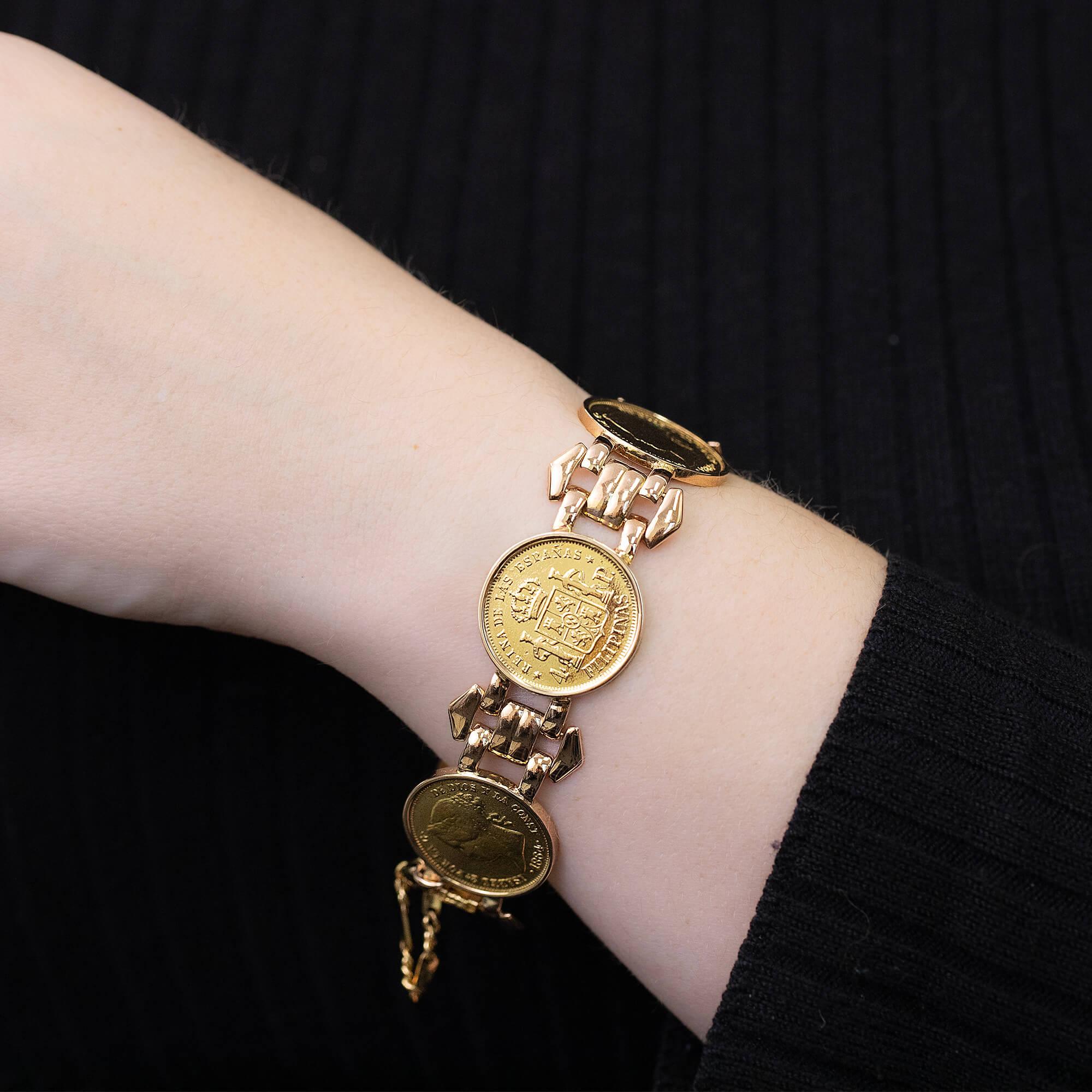 A yellow gold fancy hinged link bracelet with five bezel set coins. The coins are 1868, 4 pesos ceca de Manila (Filipinas), Isabell II. The bracelet is secured with a hinged clip clasp and safety chain. 

12 bracelet 22k coins 51.88g 4x pesos