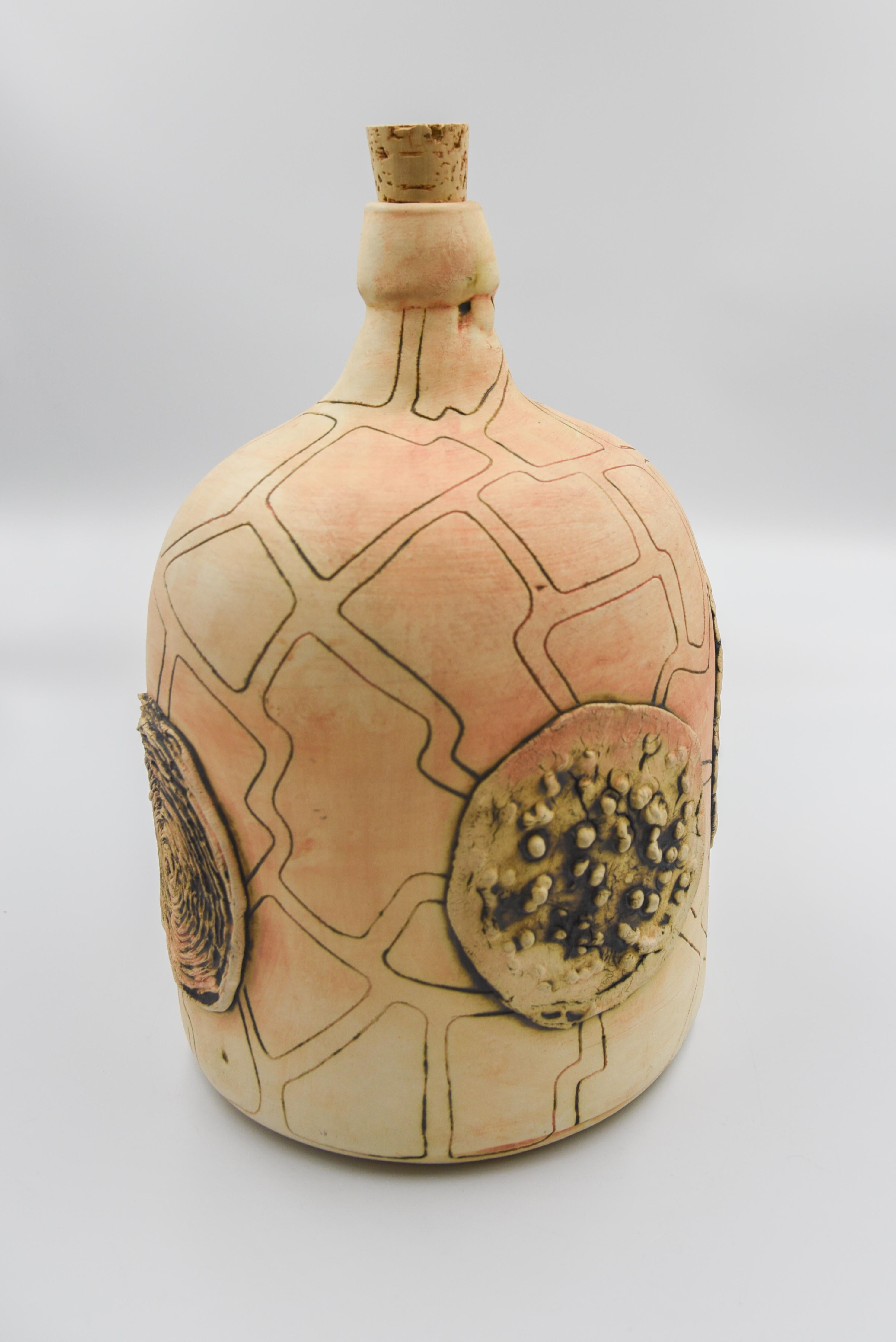 This rustic mezcal bottle is a replica of an antique bottle or demijohn which was used to store mezcal, drunken during folk theaters in Oaxaca, Mexico. The bottle is done with ceramic graffiti sgraffito technique which is later painted with oxide