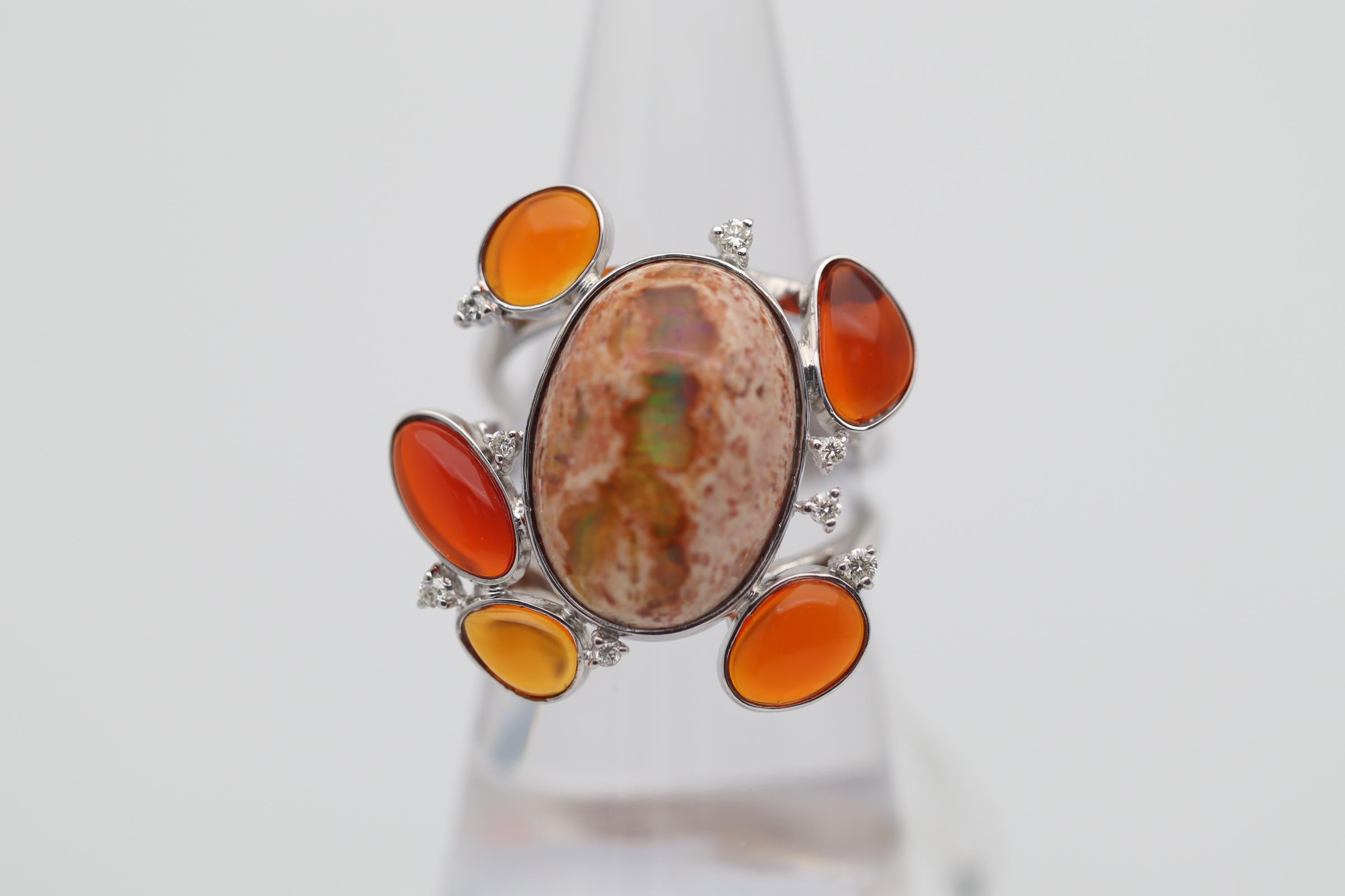 A unique, fun, and stylish ring featuring lovely fire opals! The largest opal in the center weighs 8.50 carats and is still in its original matrix for an added look. Around the center opal are 5 vivid orange/red fire opals weighing a total of 2.46