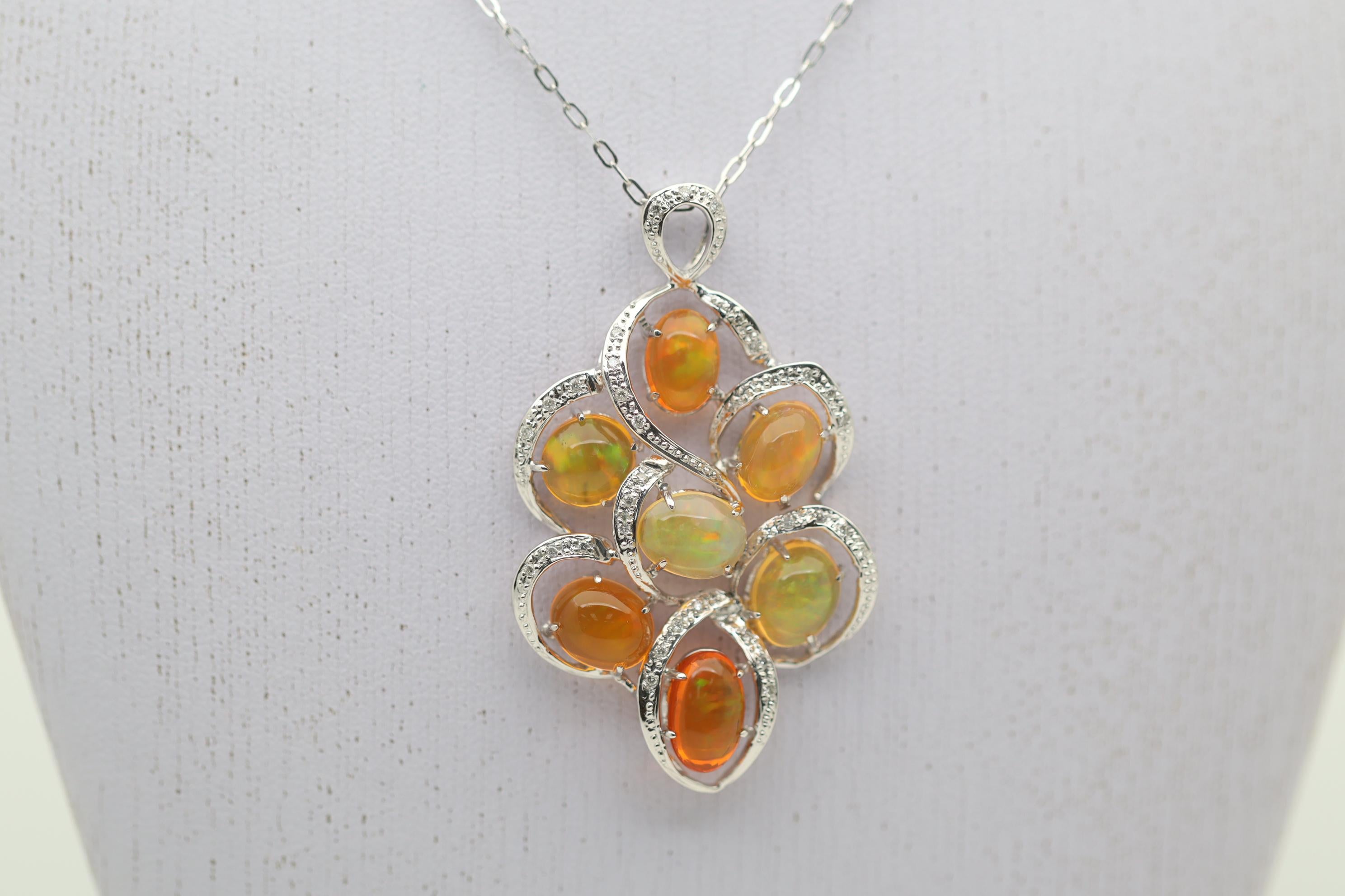 An elegant pendant featuring 7 lovely fire opals from Mexico. They weigh a total of 9.57 carats and have great play-of-color as each stone has flashes of greens and orangy-reds. Complementing the opals are 0.20 carats of round brilliant-cut diamonds