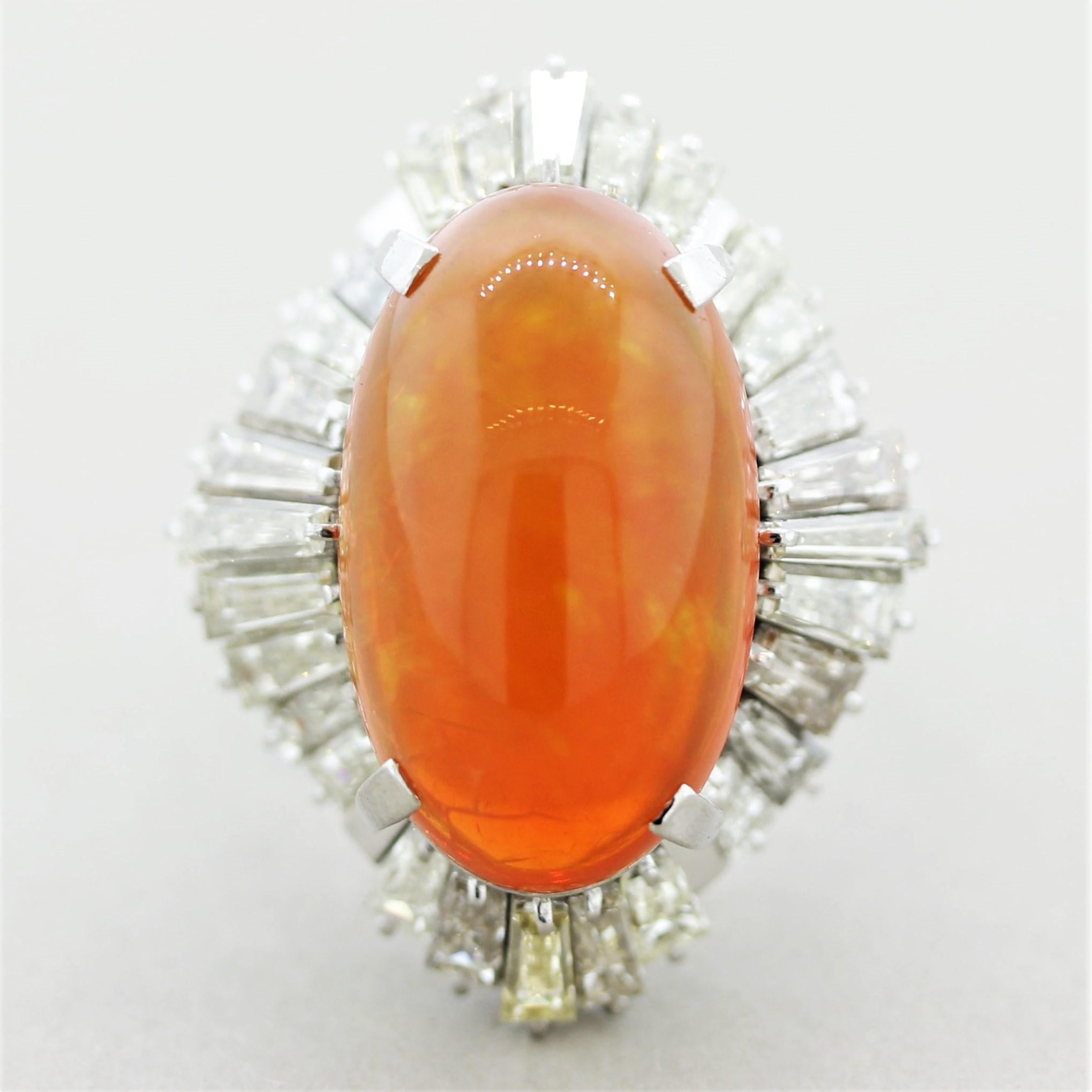 A large and impressive fire opal weighing 13.17 carats! It has a vibrant orange color with great play-of-color as flashes of red, orange, and green can be seen as the stone moves in the light. It is accented by 3.80 carats of baguette-cut diamonds