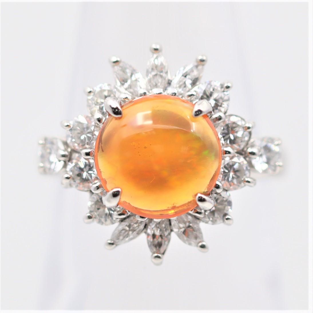 A sweet and stylish ring featuring a 1.60 carat fire opal with great play-of-color as flashes of greens, oranges, and reds can be seen running across the stone. It is accented by 1.20 carats of diamonds set around the opal in a spray design.