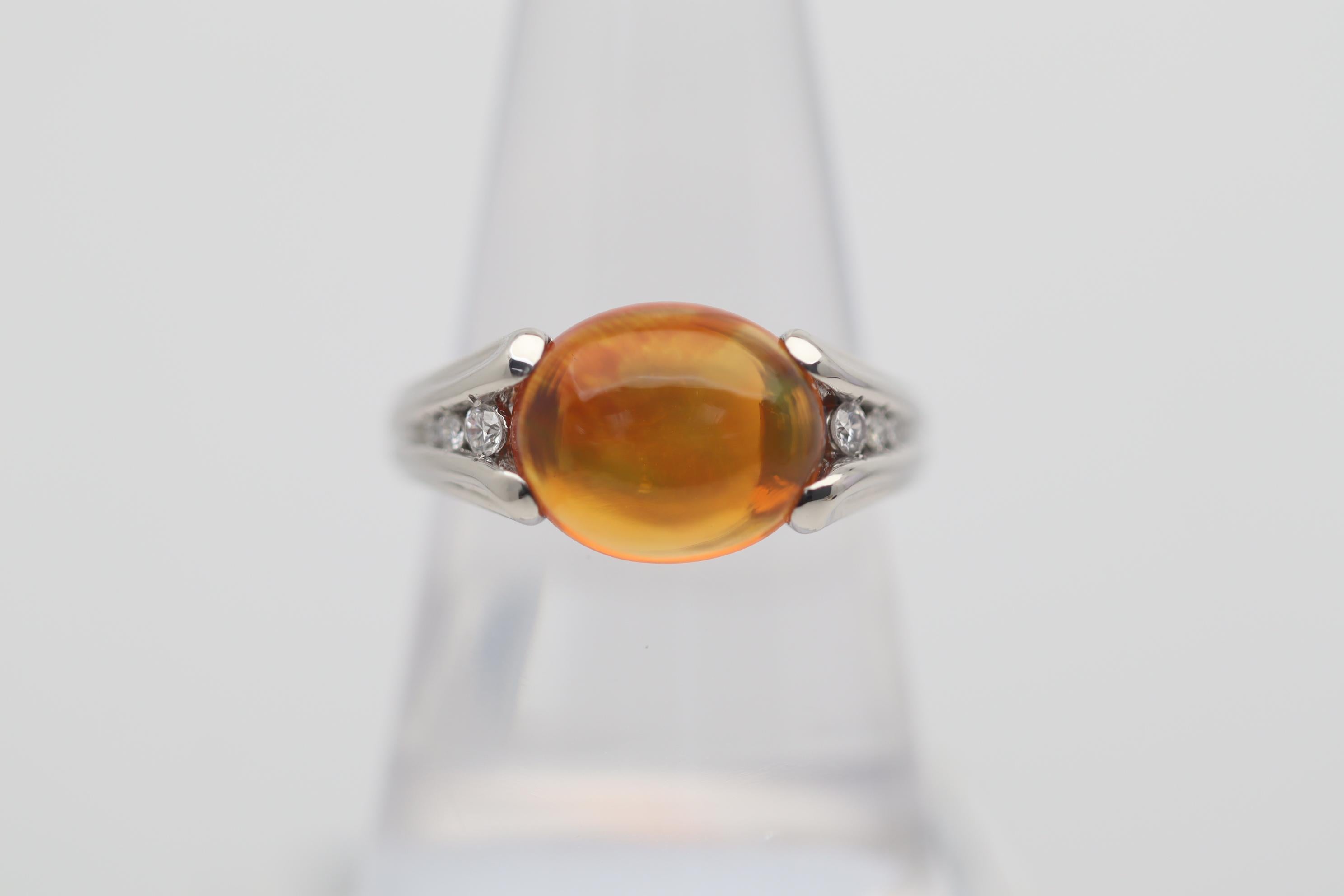 A sweet jelly fire opal from Mexico takes center stage of this platinum made ring. It weighs 3.26 carts and has a rich bright gem orange color along with strong play of color. Flashes of orange, red and green dance across the stone. It is accented