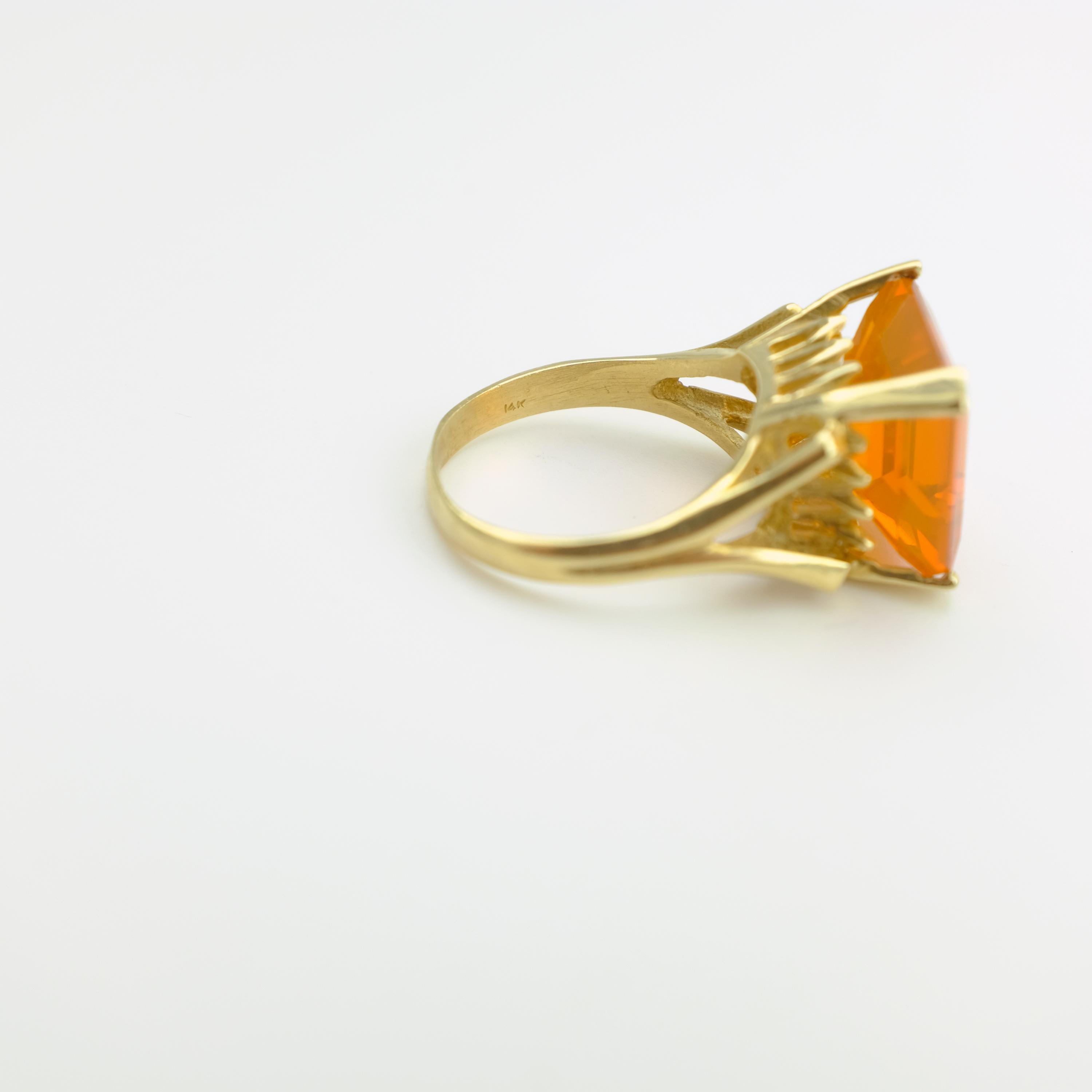 This ring is both regal and inherently eccentric. Poised high atop the finger (10.73 mm to be exact) and held aloft in a 14k yellow gold basket composed of four reverse-tapering prongs, below which is a decorative embellishment featuring a triad of