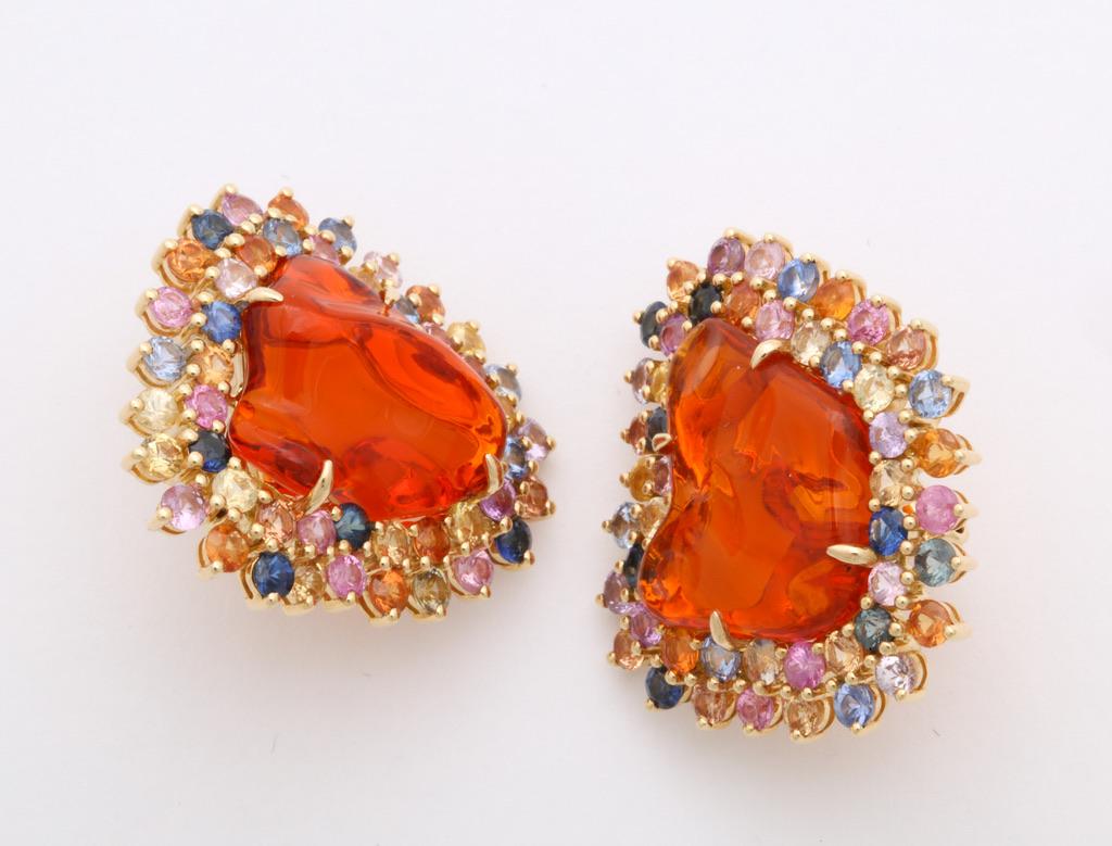 These earclips are like balls of fire on the ears, featuring Mexican fire opals framed in multi color sapphires.  The baroque shape of the stones creates a completely one of a kind design.
Mexican fire opals: app 10 carats
Sapphires: app. 6 1/2