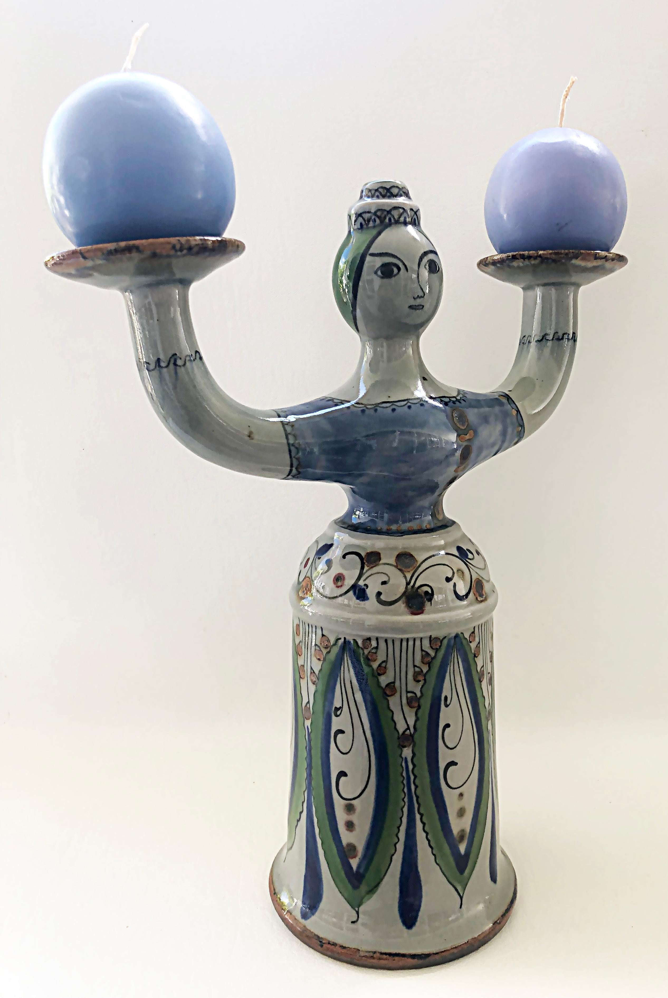 Mexican hand-painted Tonala Pottery 2-arm candelabra, signed.

Offered for sale is a Mexican Tonala pottery two-arm candelabra depicting a woman hand-painted with a typical embroidered dress and outstretched arms which serve as the candleholders.