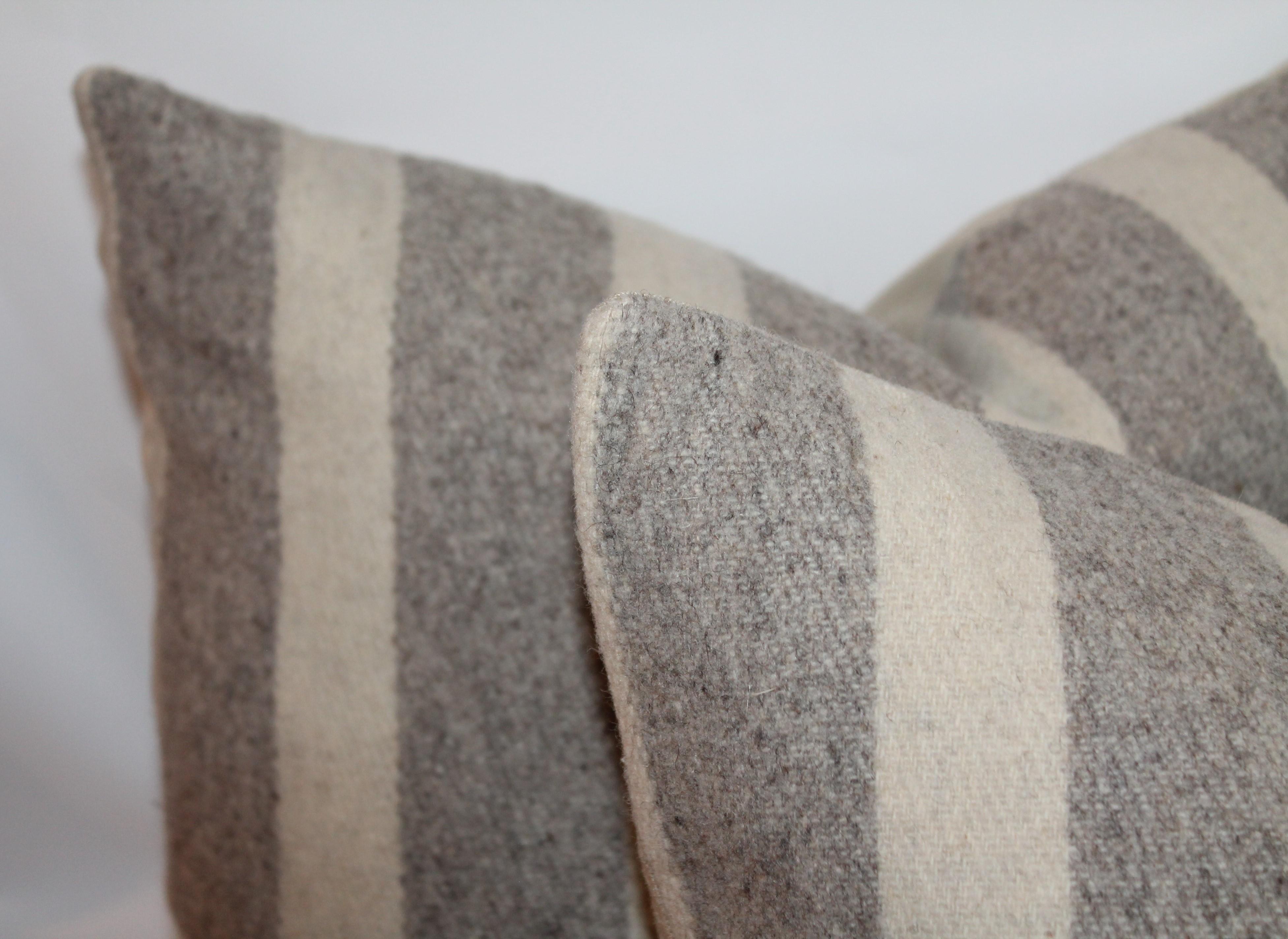 Handwoven Mexican Indian weaving pillows in pristine condition with grey cotton linen backing. The pillows are in cream and grey striped wool. The inserts are in down and feather filled.