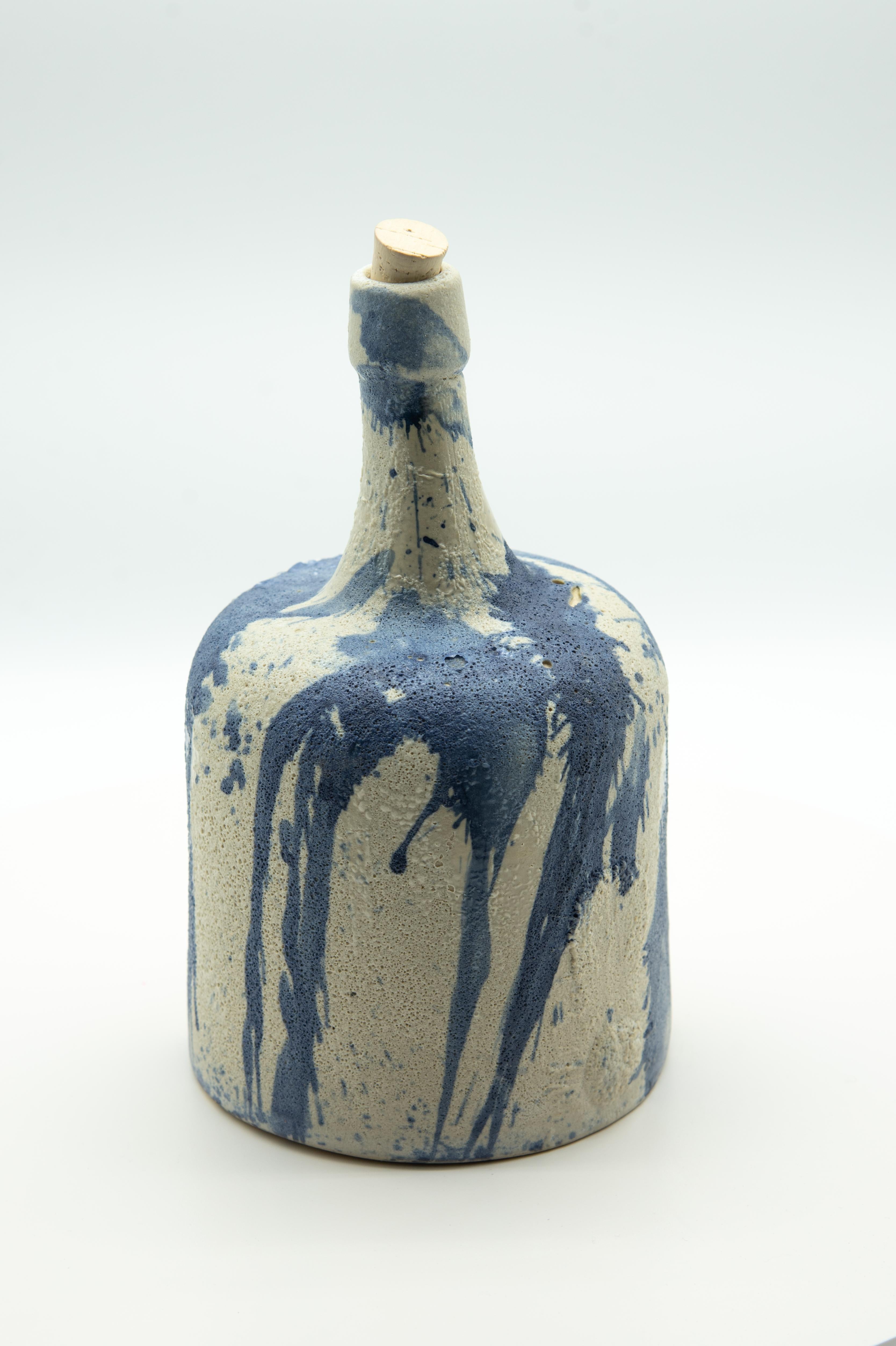 Diese rustikale Mezcalflasche ist eine Nachbildung einer antiken Flasche oder eines Demijohns, der zur Aufbewahrung von Mezcal verwendet wurde, der bei Volkstheatern in Oaxaca, Mexiko, getrunken wurde. Die Keramikflasche ist mit Kobalt bemalt, was